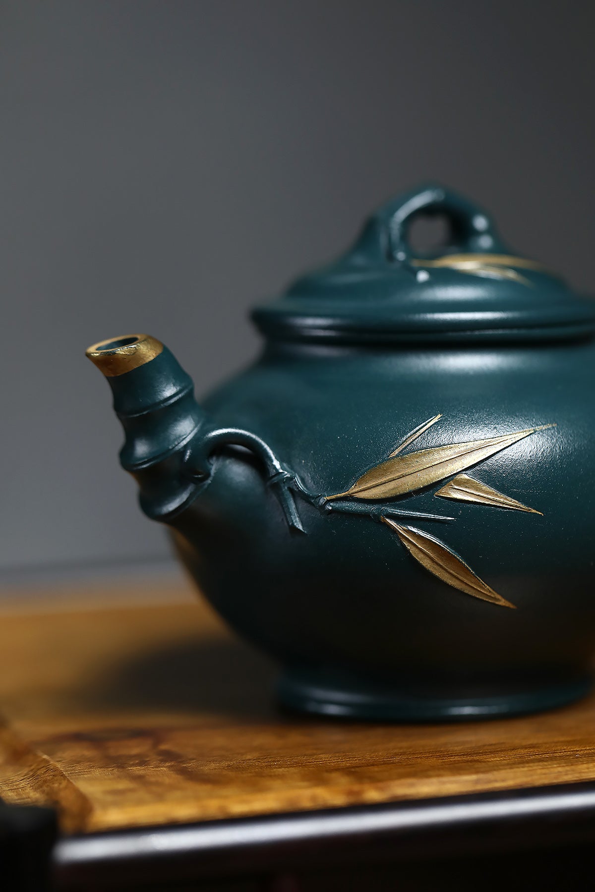 Handmade Yixing purple sand teapot with bamboo leaf design in rich green color, showcasing artistry in traditional craftsmanship.