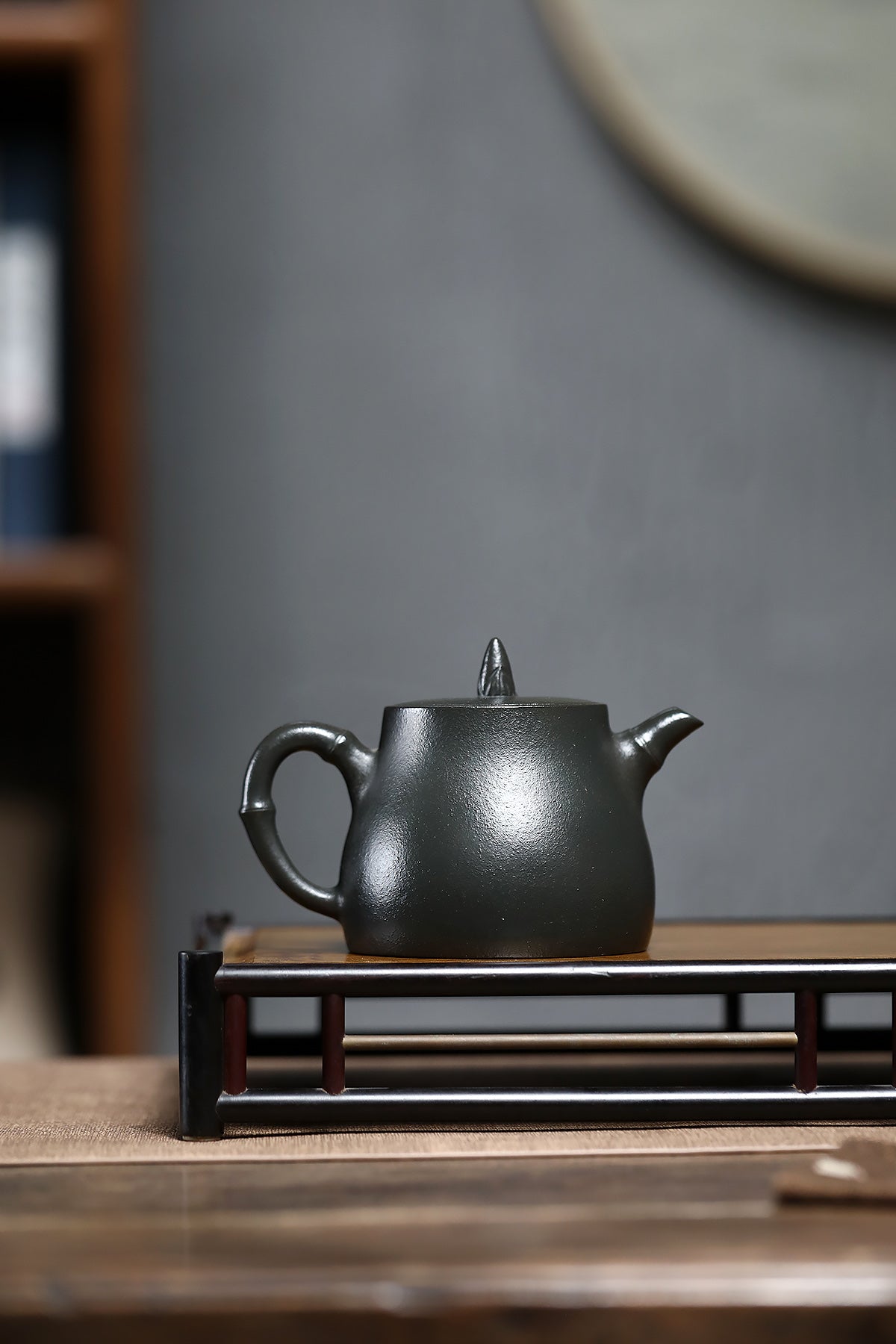 Handmade Yixing purple sand teapot in a simple design, showcasing its elegant dark finish on a wooden tray.