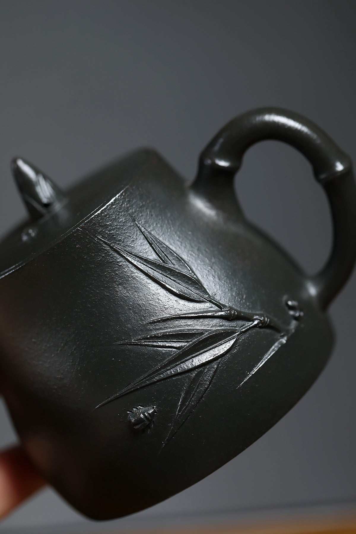 Handmade Yixing purple sand teapot with bamboo design, featuring a smooth black finish and natural textures.