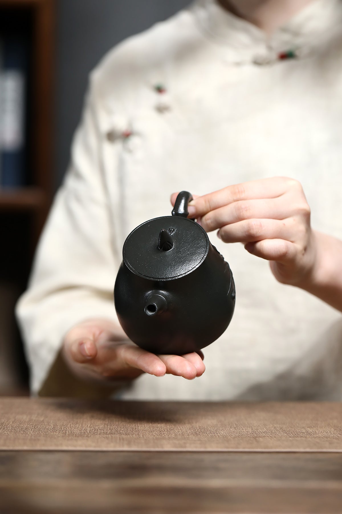 Handmade Yixing purple sand teapot held by a person, showcasing its unique design and craftsmanship.