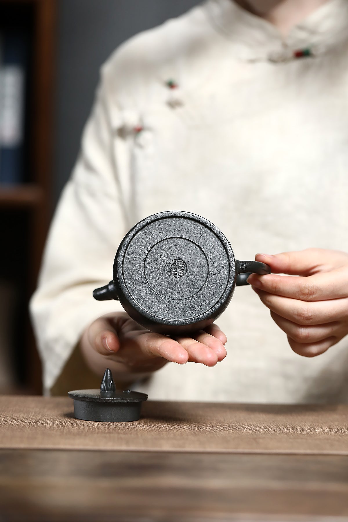 Handmade Yixing purple sand teapot showcased by a craftsman, highlighting its unique texture and design.