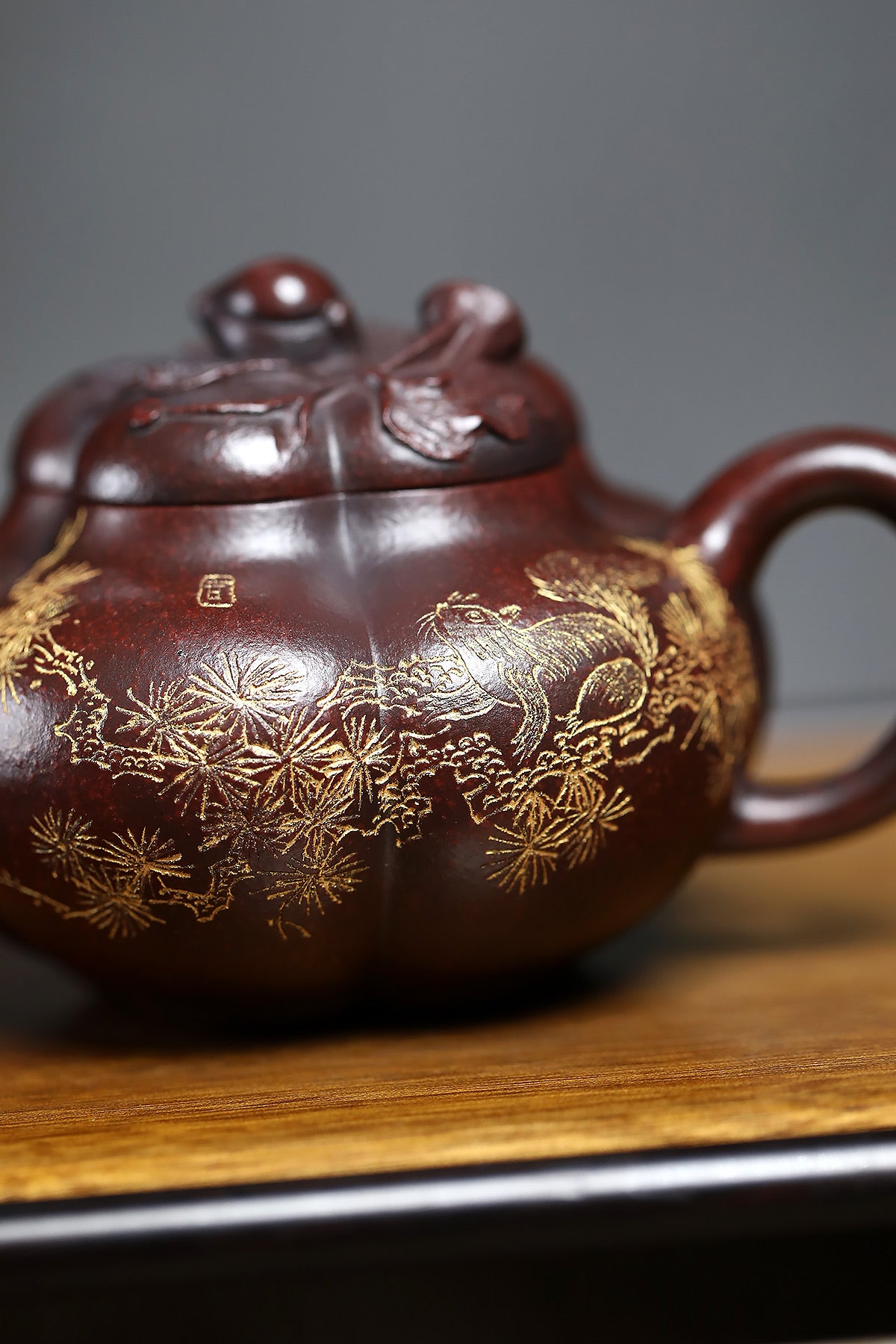 Handmade Yixing purple sand teapot with gold leaf design featuring a playful animal and floral motifs.