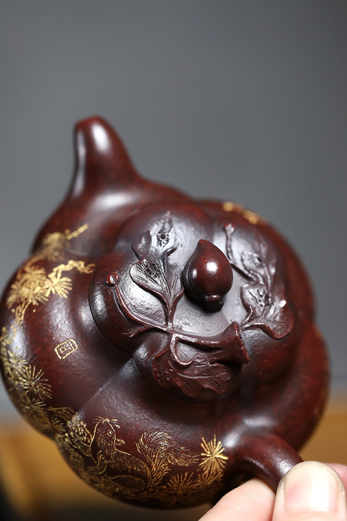 Handmade Yixing purple sand teapot with intricate carvings and a glossy finish, showcasing traditional craftsmanship.