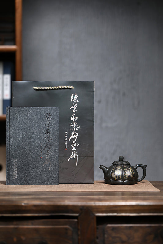 Handmade Yixing purple sand teapot with elegant black packaging and accompanying booklet on wooden table.