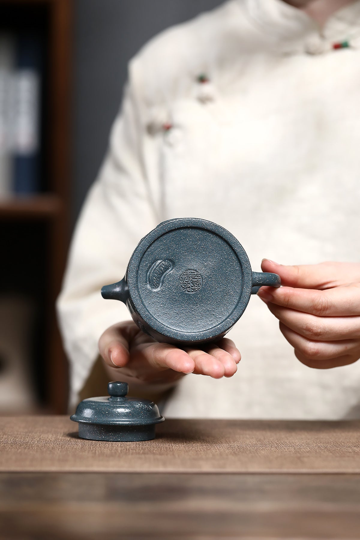 Handmade Yixing purple sand teapot held by a craftsman, showcasing its polished finish and unique design.