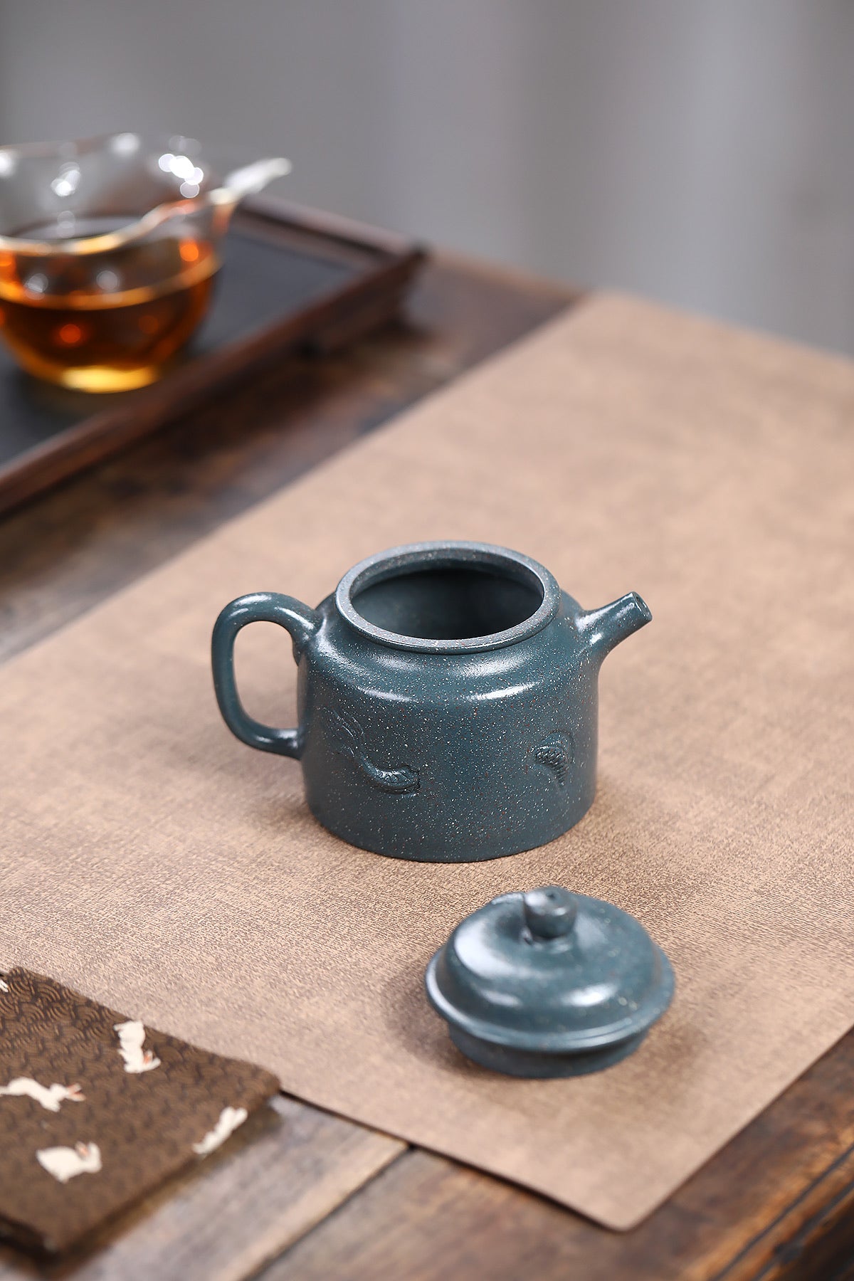 Handmade Yixing purple sand teapot, dark blue glaze, with lid, elegant design on tea table.