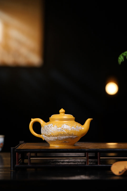 Handmade Yixing purple sand teapot in vibrant yellow with intricate white designs, elegantly displayed on a wooden tray.