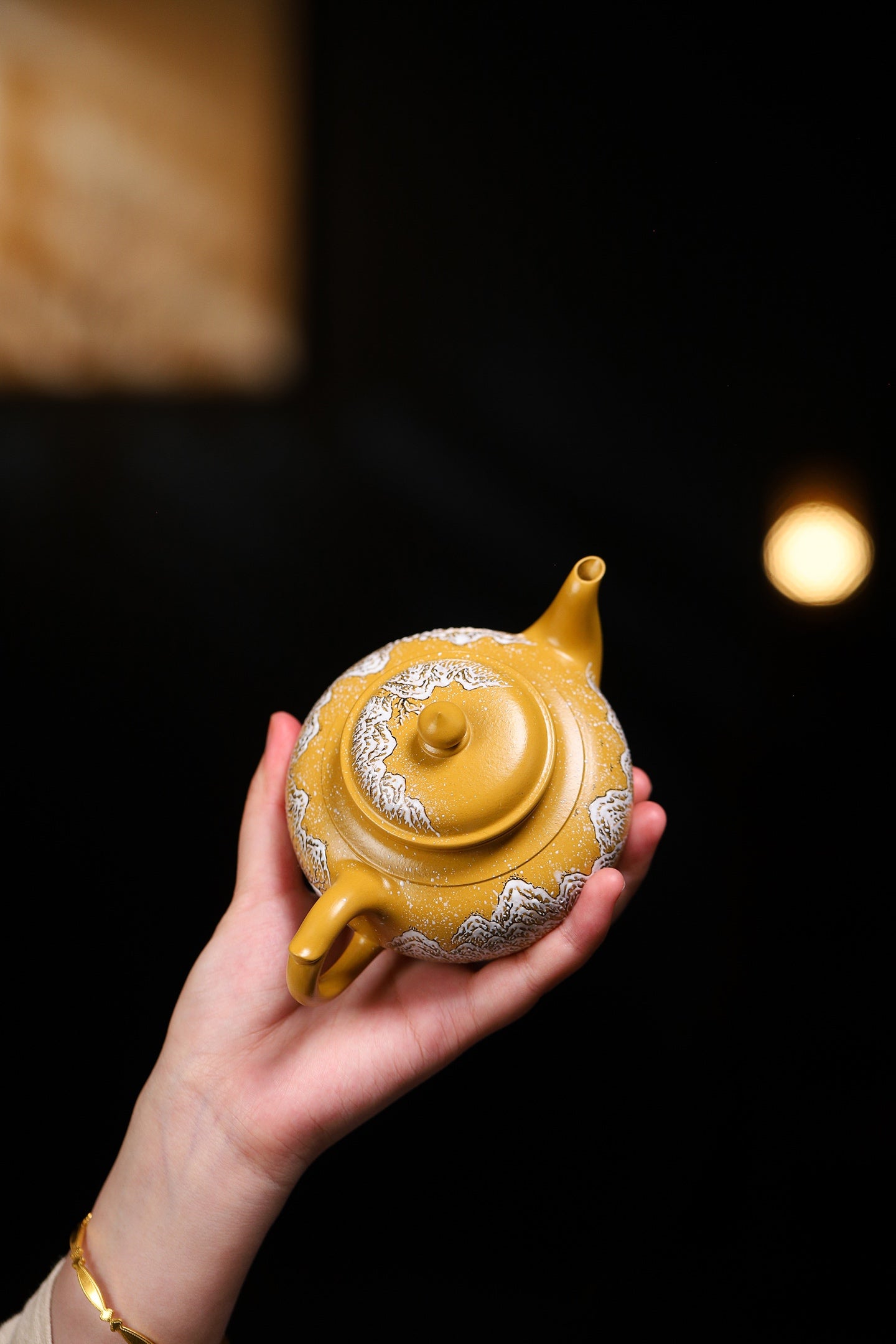 Handmade Yixing purple sand teapot in hand, showcasing elegant design and craftsmanship.