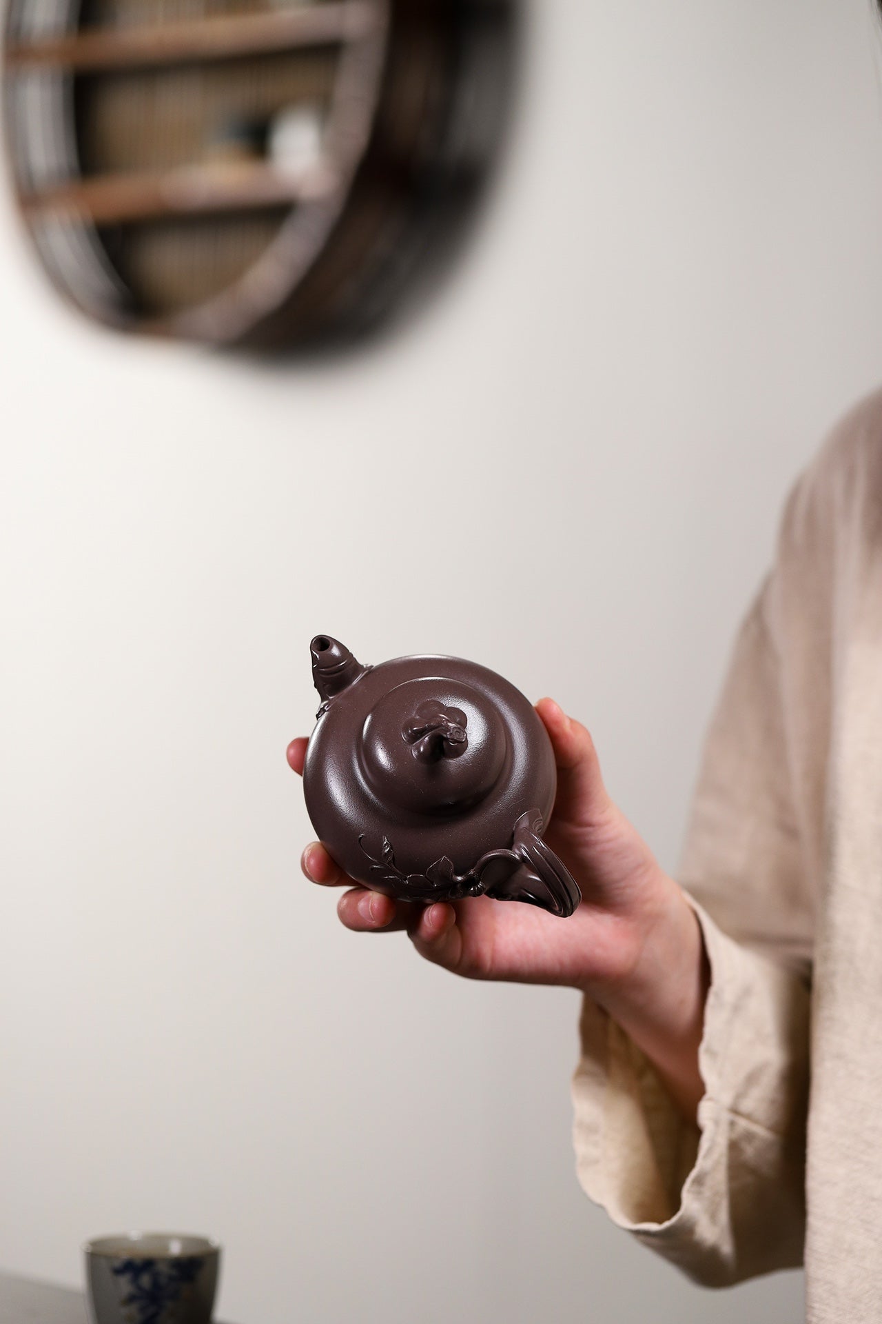 Handmade Yixing purple sand teapot in hand, showcasing unique design and craftsmanship, ideal for tea enthusiasts.