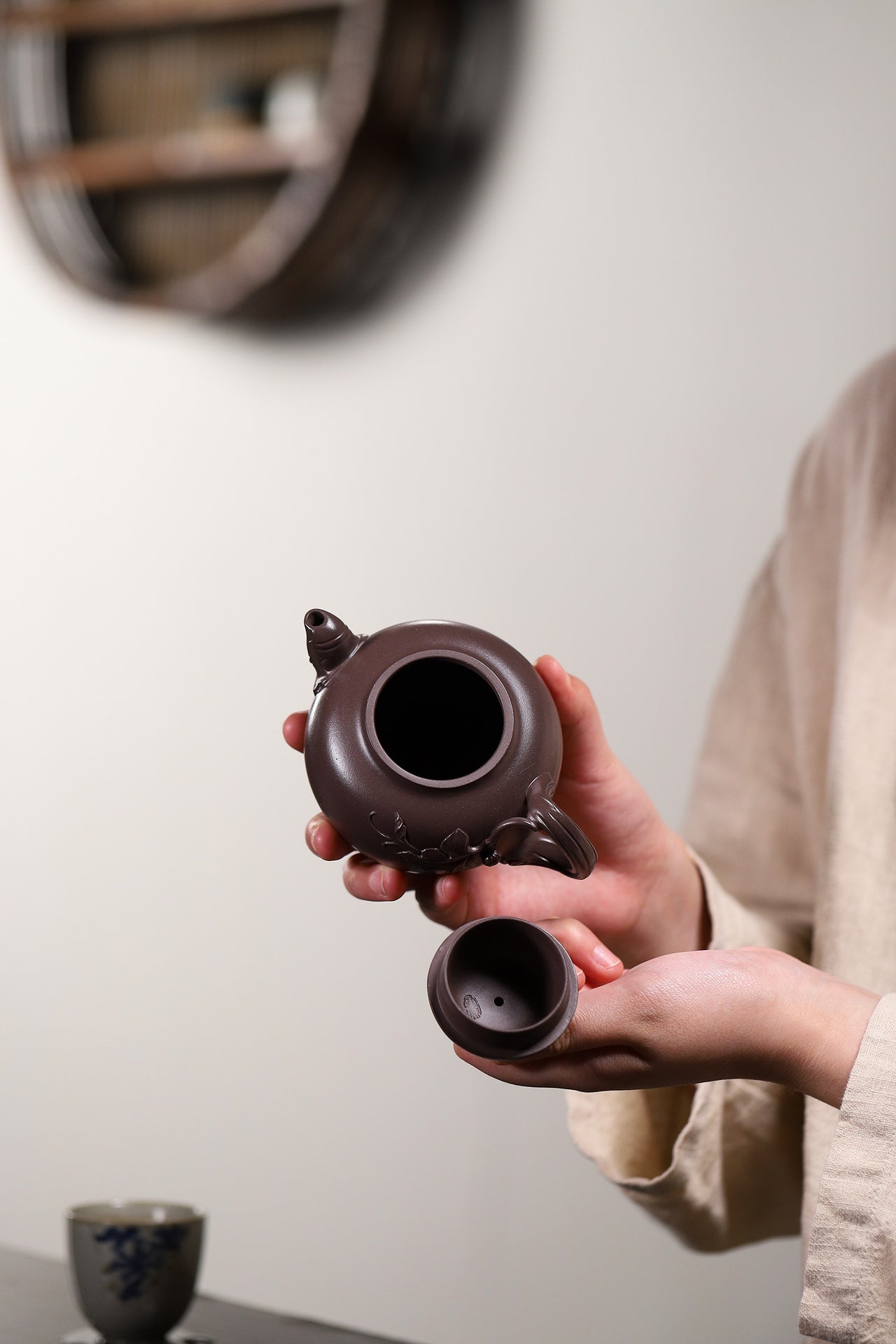 Handmade Yixing purple sand teapot held by a person, showcasing unique design and craftsmanship.