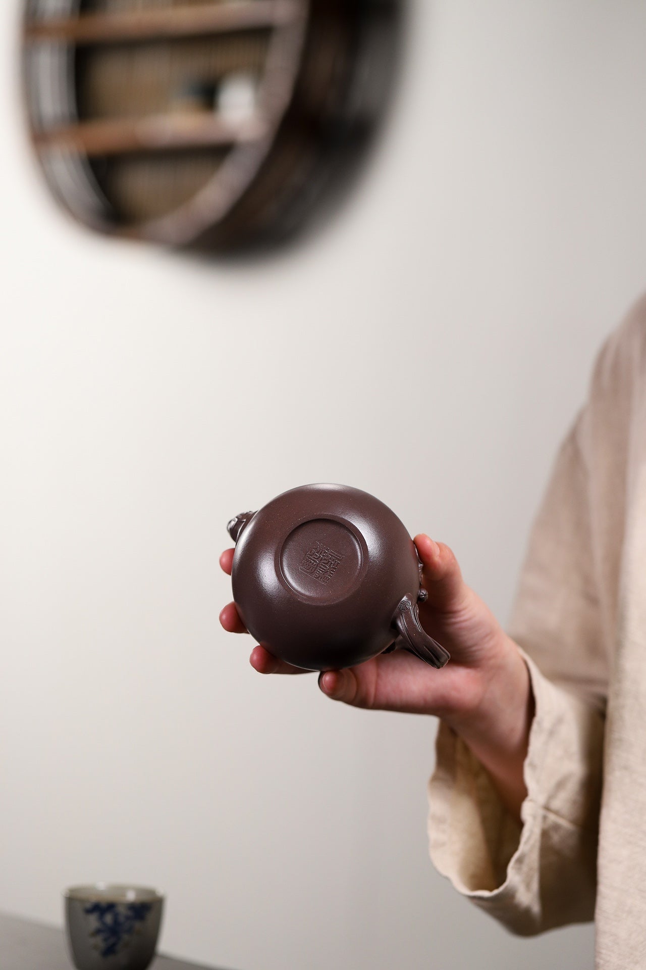 Handmade Yixing purple sand teapot held in hand, showcasing unique design and fine craftsmanship.