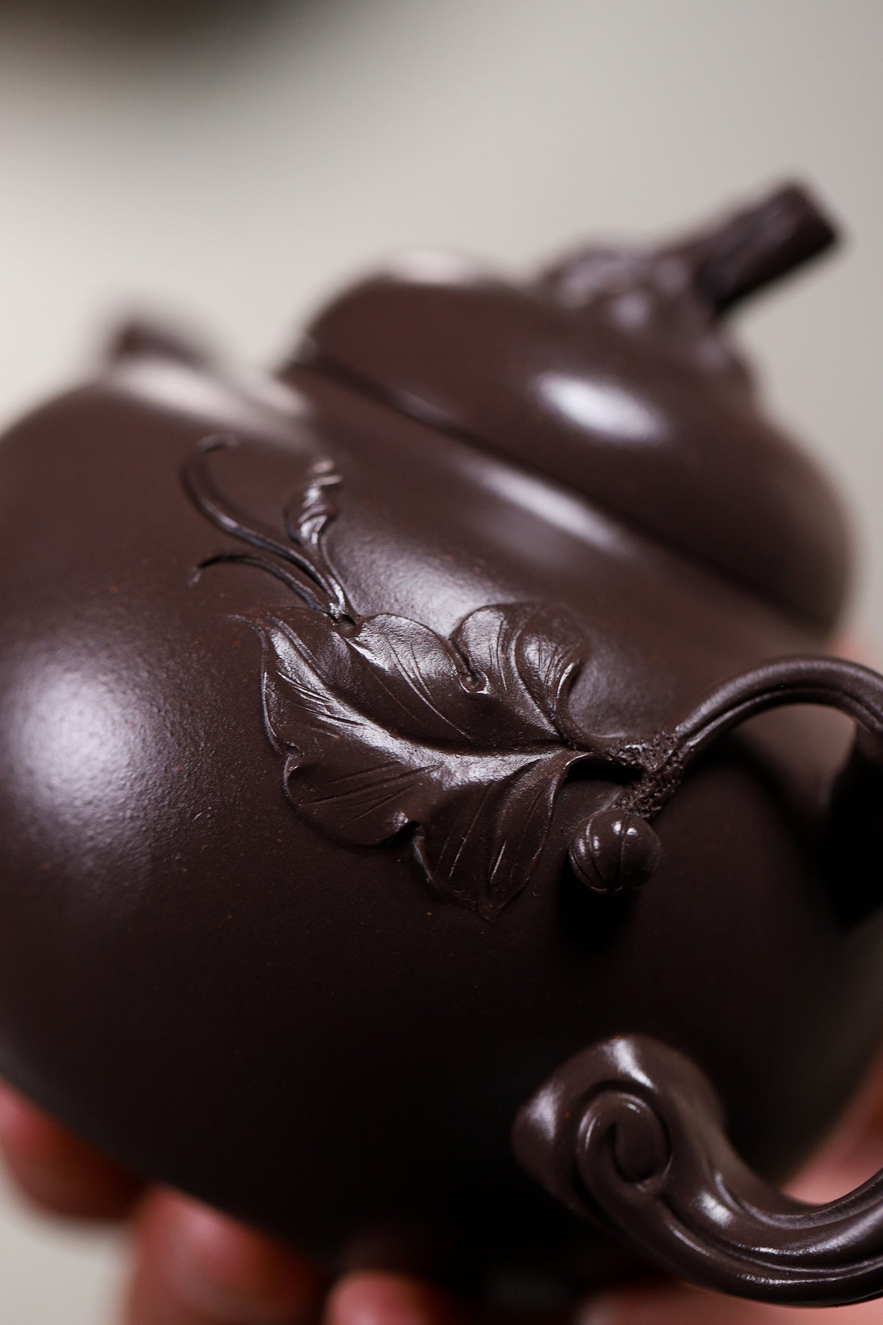 Handmade Yixing purple sand teapot featuring intricate leaf design, showcasing exceptional craftsmanship and detail.
