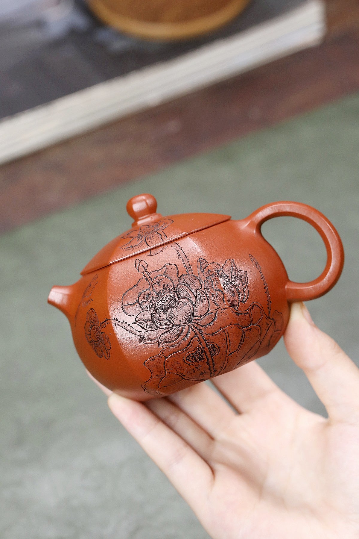 Handmade Yixing purple sand teapot featuring intricate lotus engraving, showcasing natural beauty and craftsmanship.