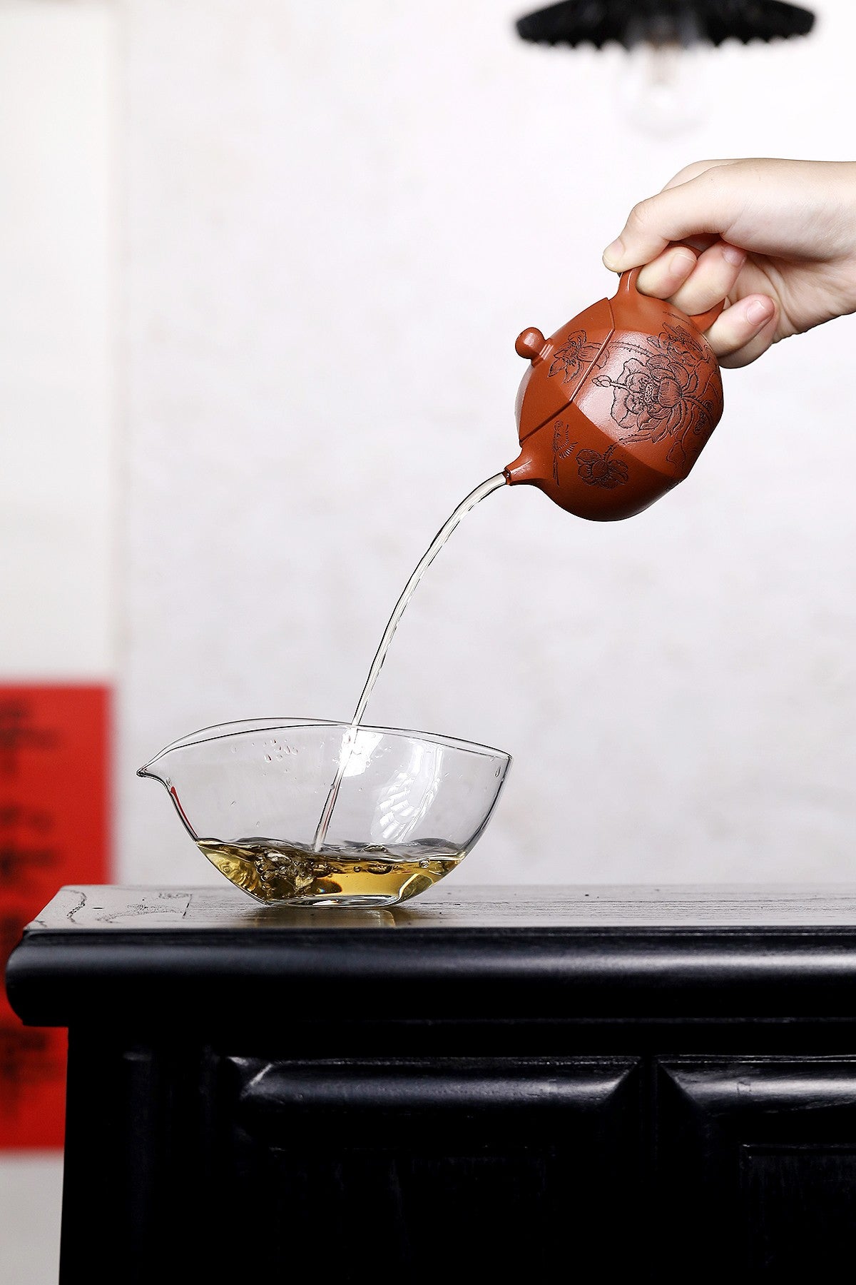 Pouring tea from a handmade Yixing purple sand teapot into a glass bowl, capturing the essence of traditional tea culture.
