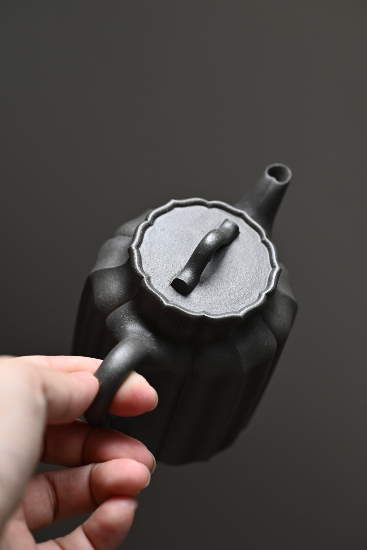 Handmade Yixing purple sand teapot, showcasing elegant design and fine craftsmanship, held in a person's hand.