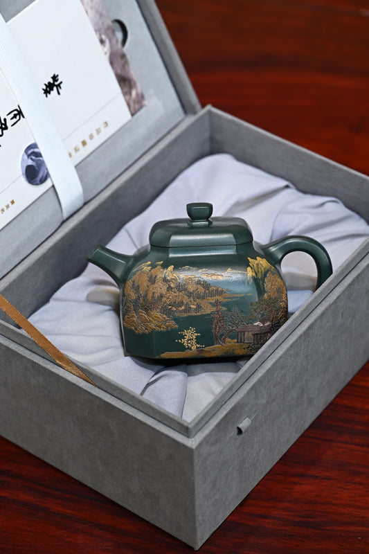 Handmade Yixing purple sand teapot in a gray gift box, showcasing intricate natural landscape design.