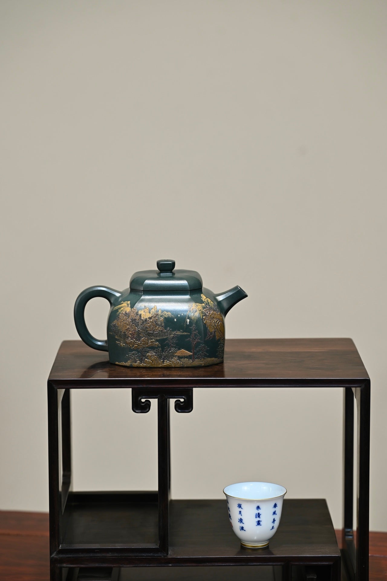 Handmade Yixing purple sand teapot on a wooden stand with a blue and white teacup.