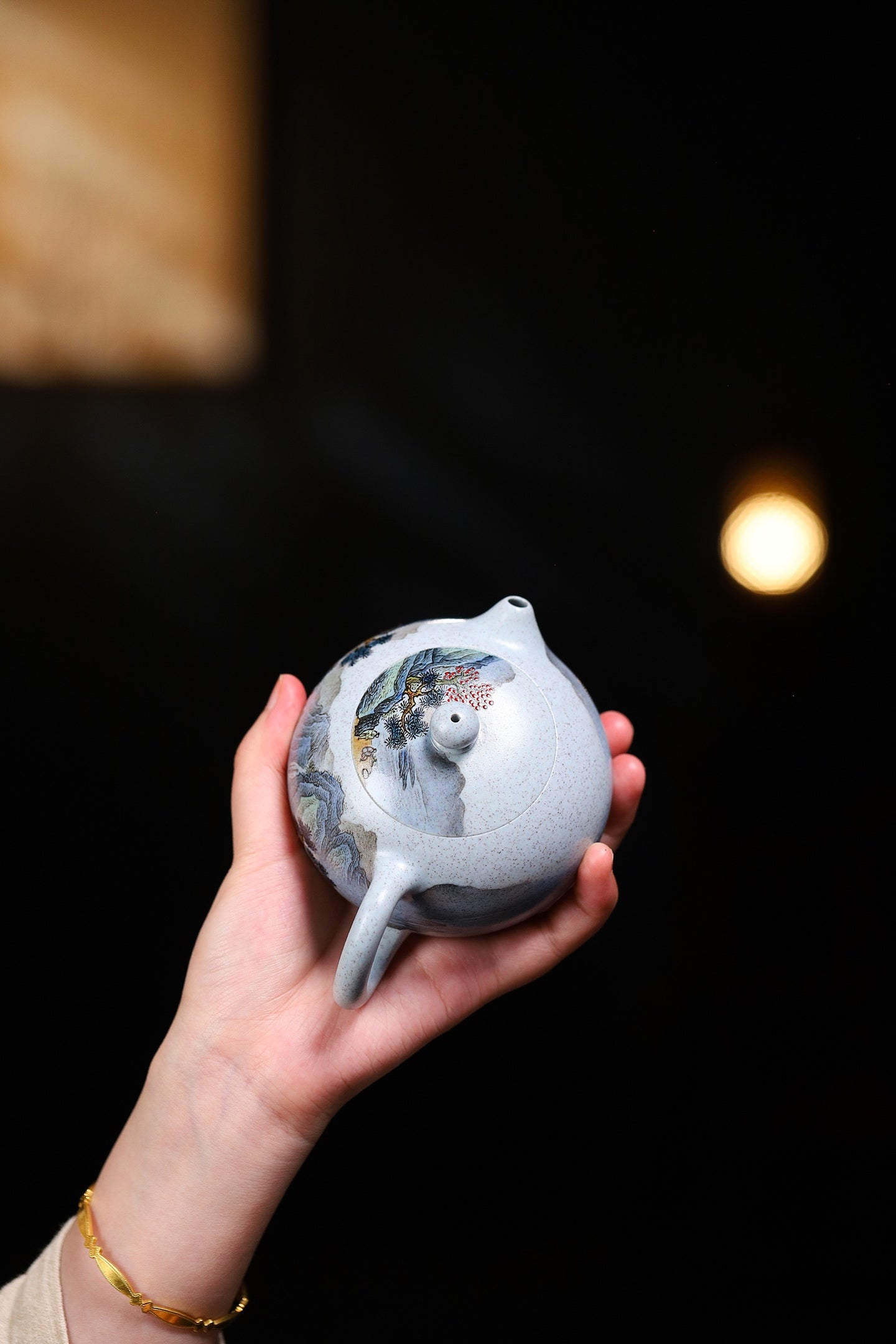 Handmade Yixing purple sand teapot held in hand, showcasing unique design and craftsmanship.