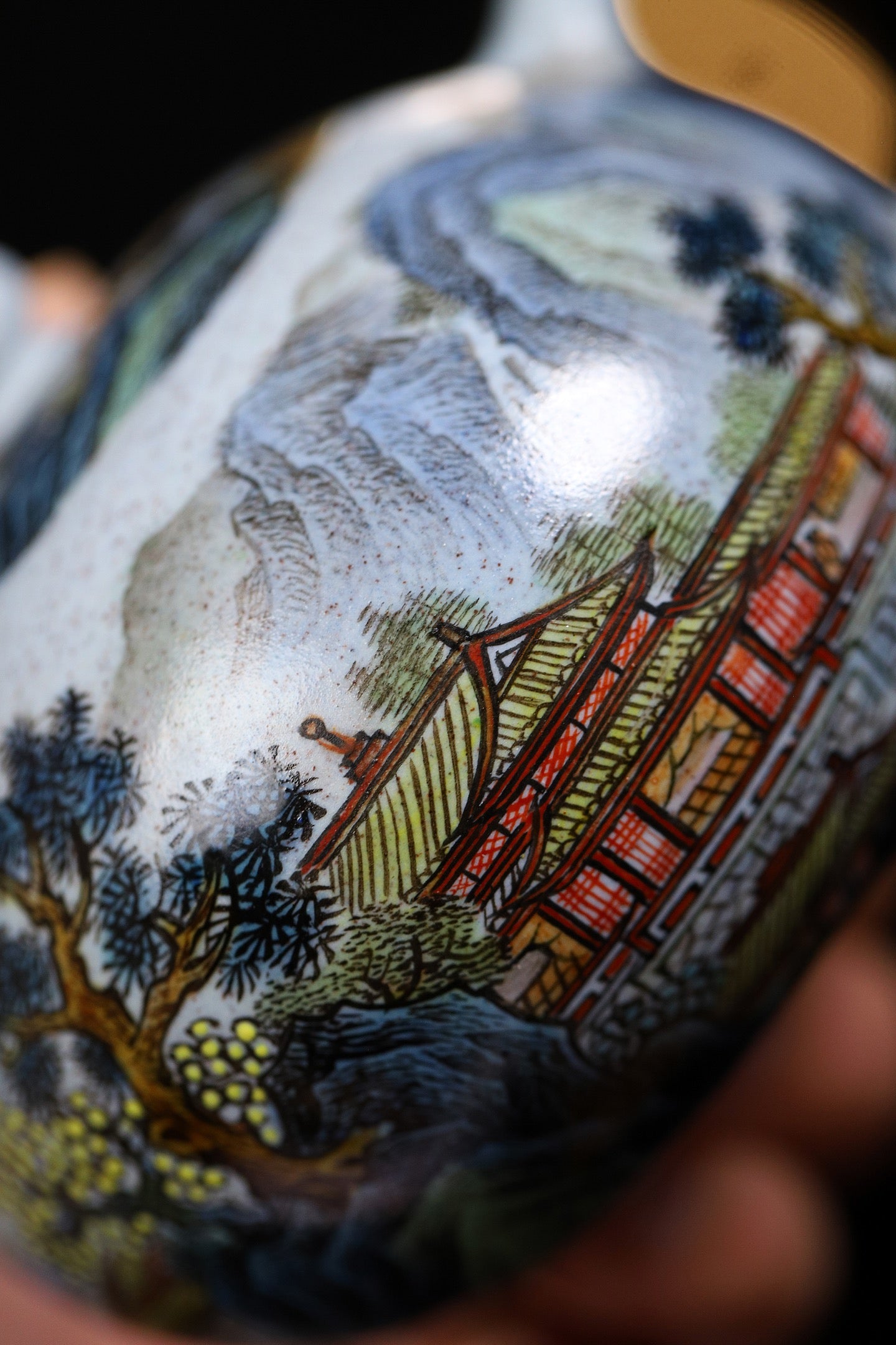 Hand-painted Yixing teapot showcasing intricate landscape design with traditional architecture and nature elements.