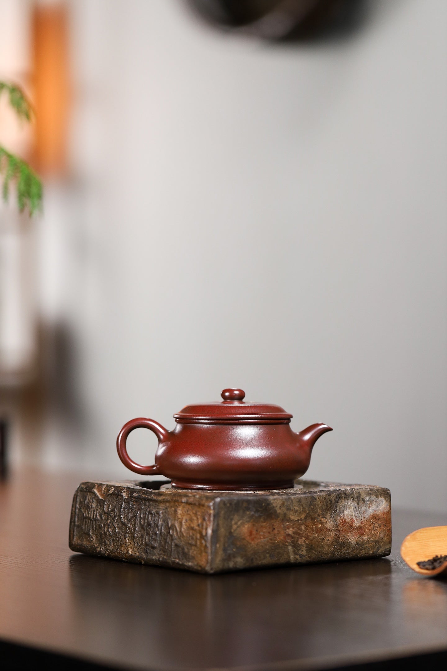 Handmade Yixing purple sand teapot on wooden base, showcasing elegant design and craftsmanship.