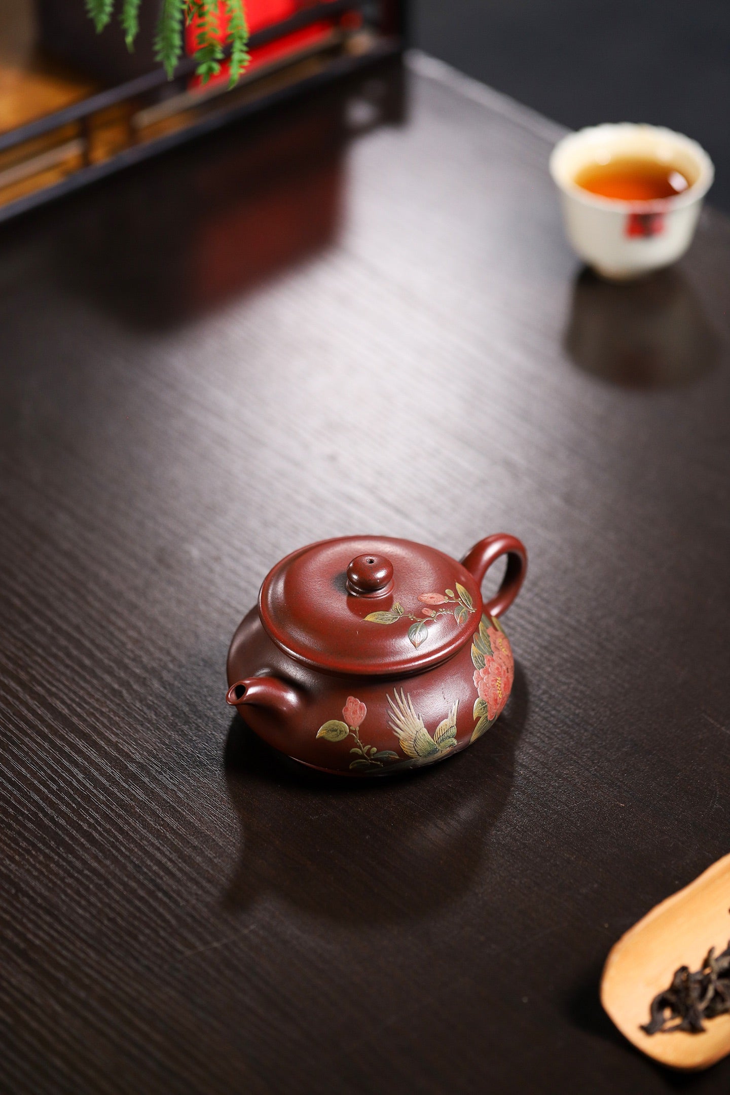 Handmade Yixing purple sand teapot with floral design on a wooden table, perfect for tea enthusiasts.