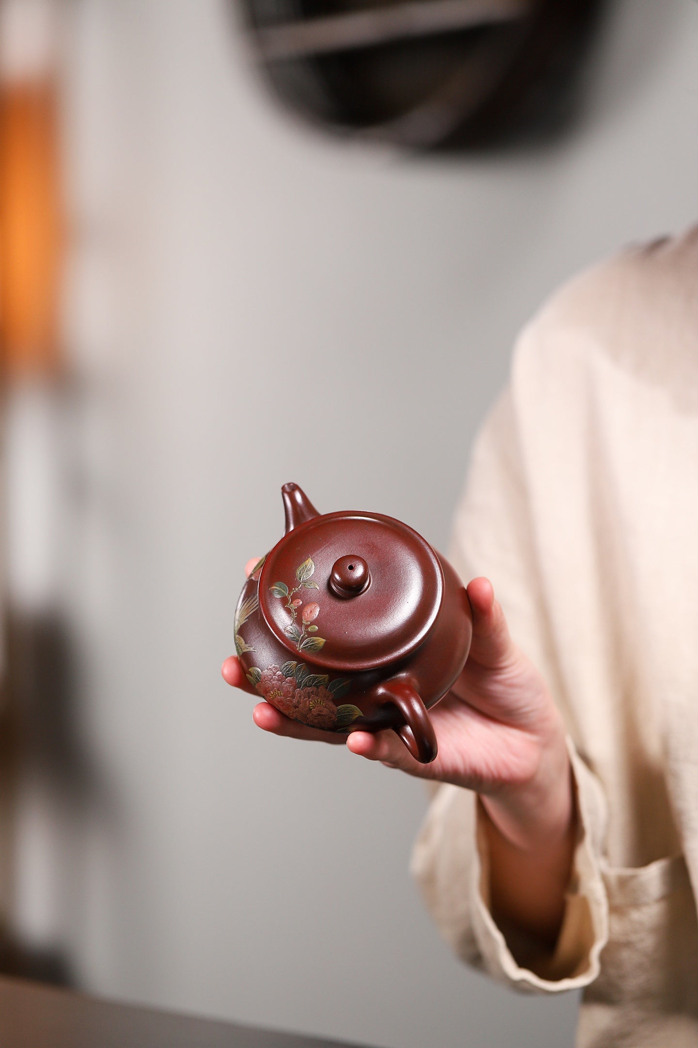 Handmade Yixing purple sand teapot, elegantly held, showcasing intricate design and craftsmanship.