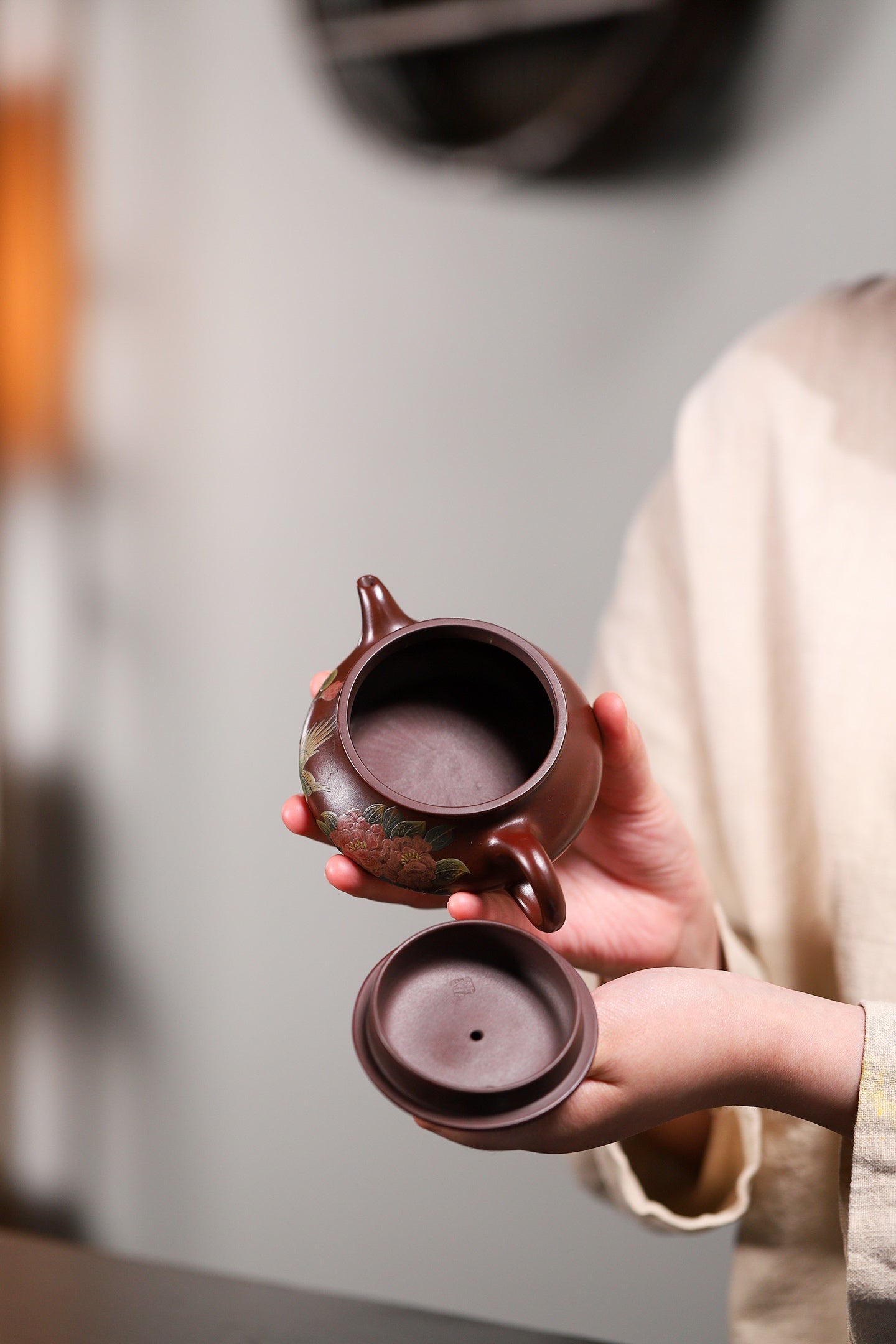 Handmade Yixing purple sand teapot, showing elegant design and craftsmanship, held by a person.