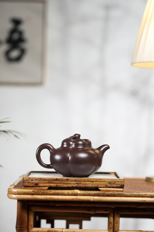 Handmade Yixing purple sand teapot on a bamboo tray, showcasing a unique and elegant design.
