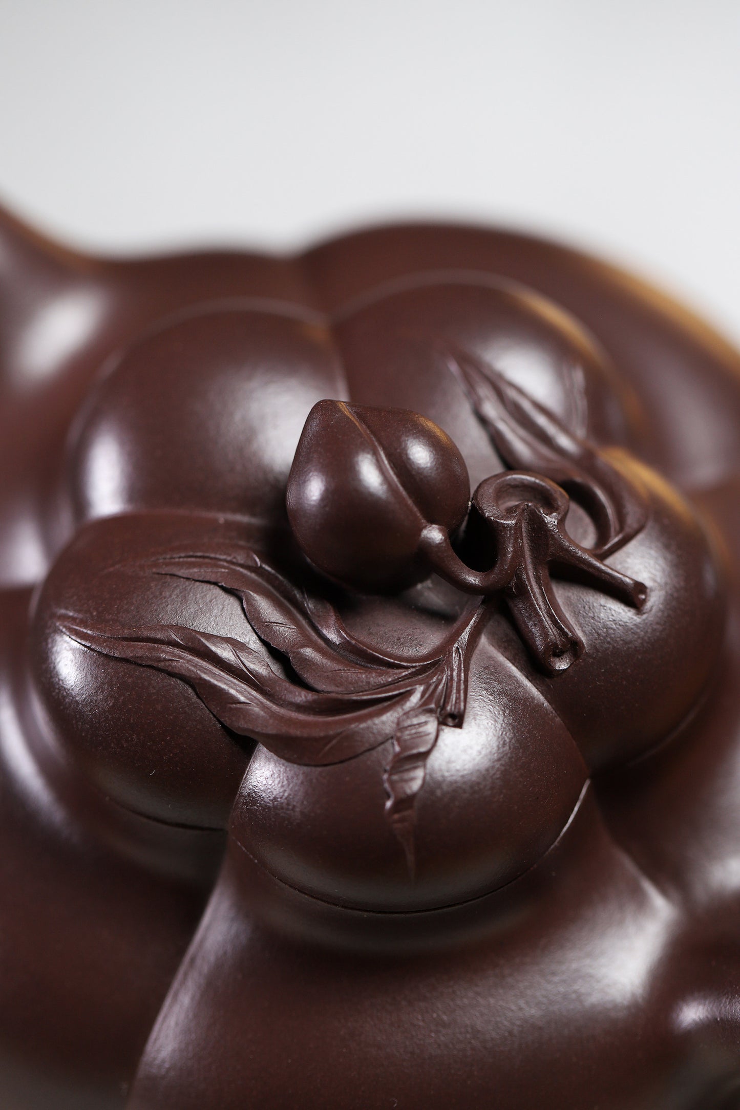 Handmade Yixing purple sand teapot lid with intricate peach motif, showcasing fine craftsmanship and details.