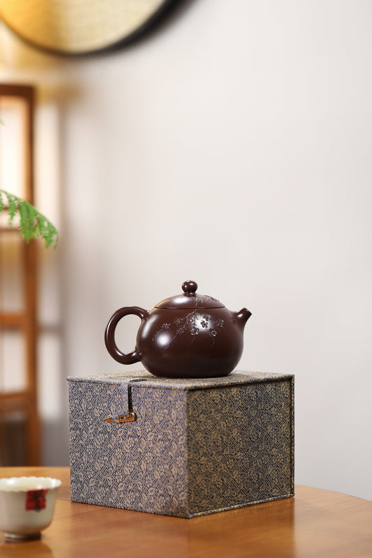 Handmade Yixing purple sand teapot on decorative box, showcasing traditional craftsmanship and elegant design.