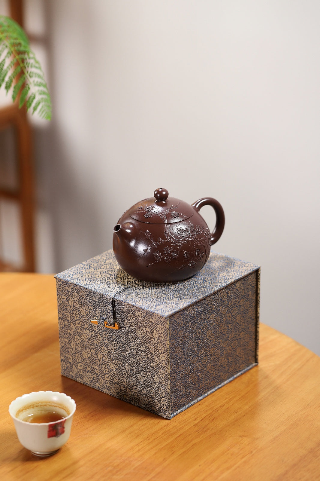 Handmade Yixing purple sand teapot on a decorative box, showcasing its elegant design and fine craftsmanship.