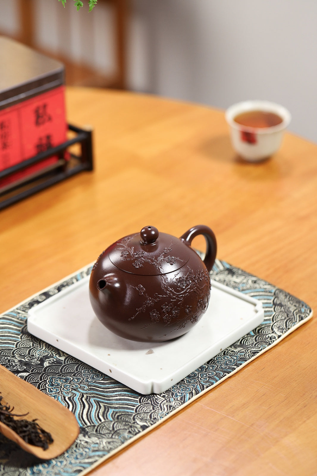 Handmade Yixing purple sand teapot on a decorative tray with tea and accessories.