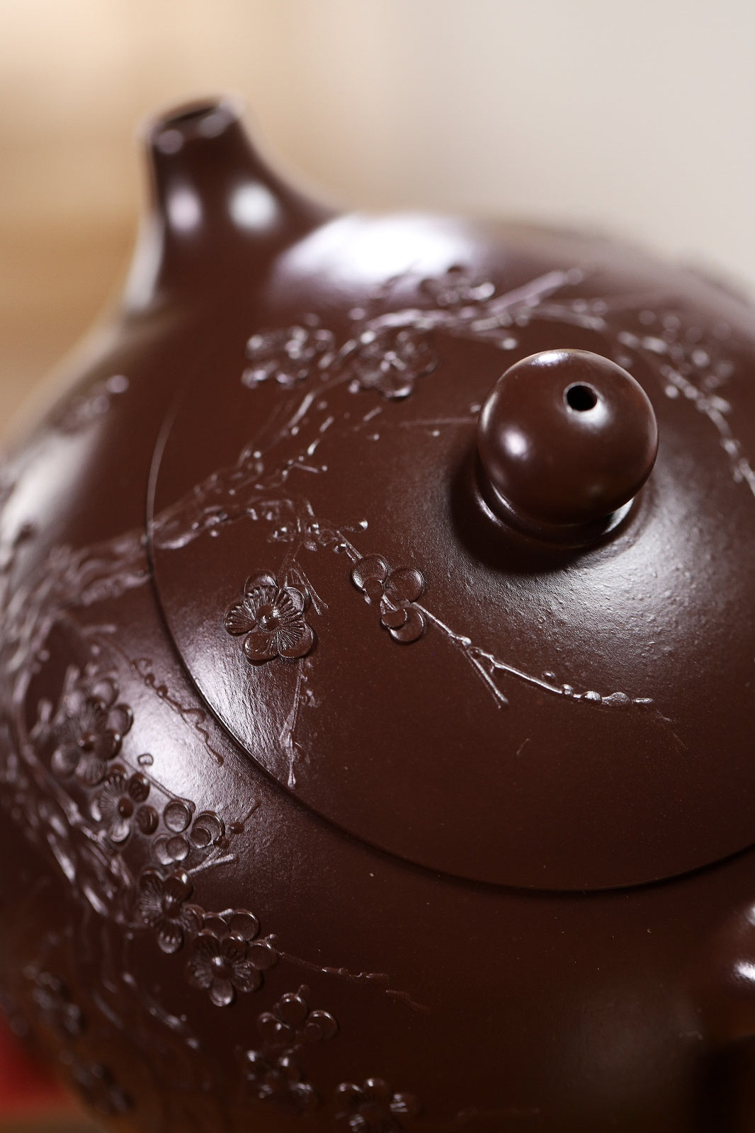 Handmade Yixing purple sand teapot featuring intricate floral carving and a smooth rounded lid.