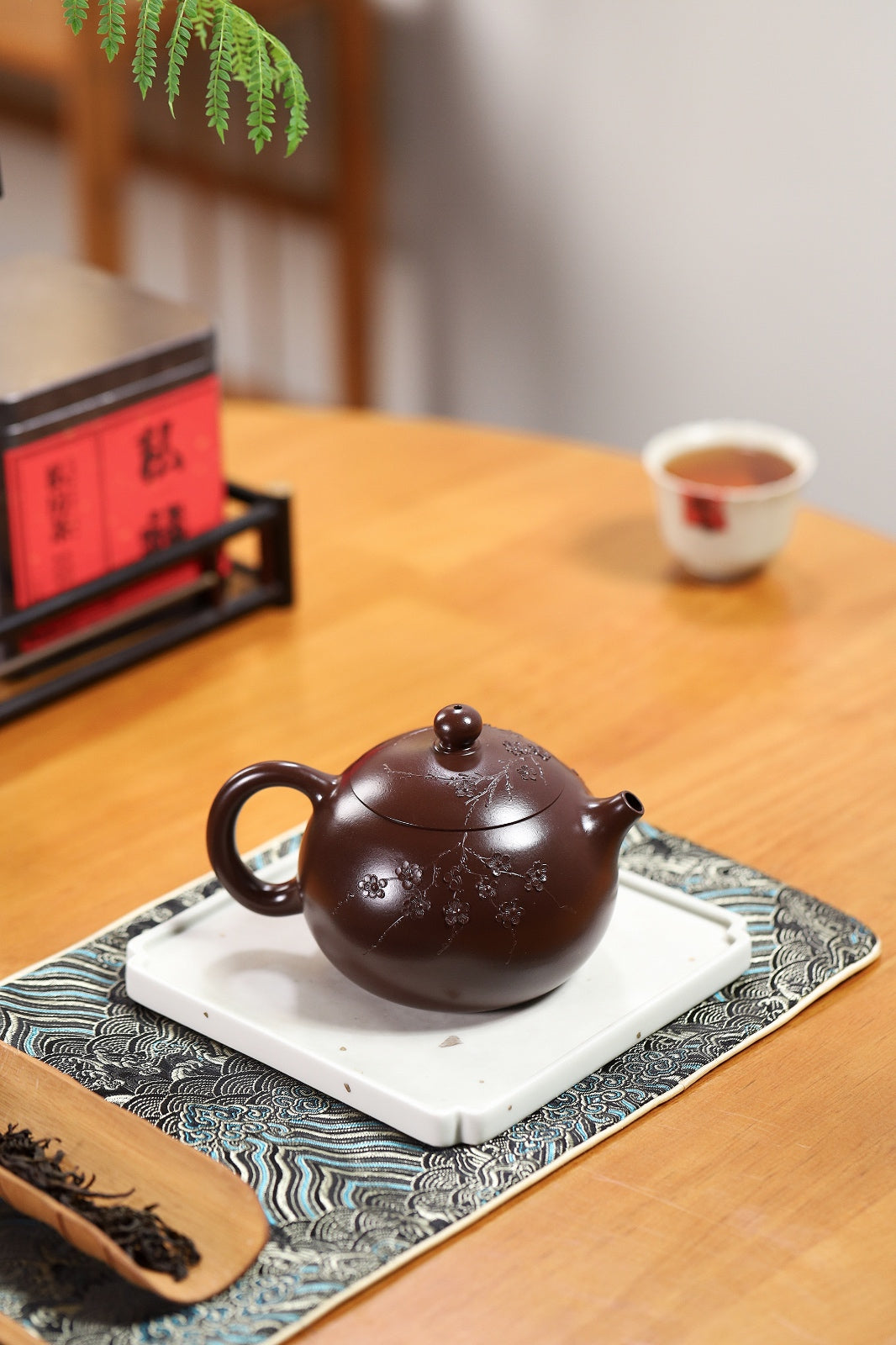 Handmade Yixing purple sand teapot on a decorative tray, showcasing elegant craftsmanship and traditional design.