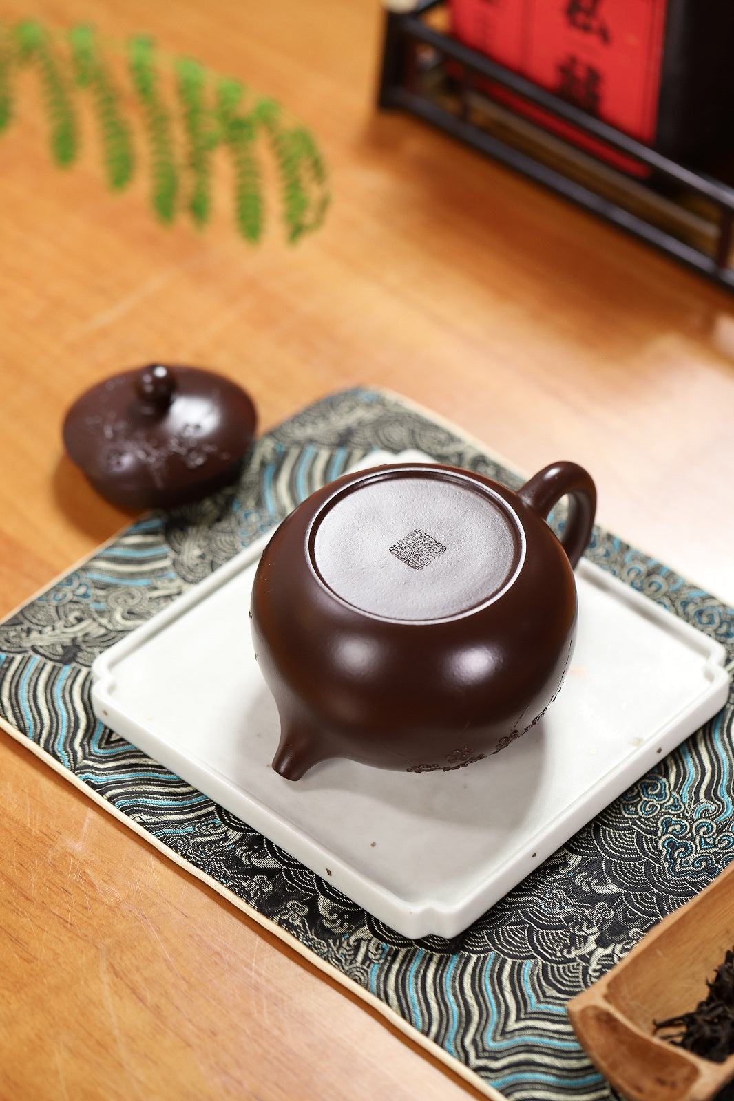 Handmade Yixing purple sand teapot on a decorative tray, showcasing its rich texture and elegant design.