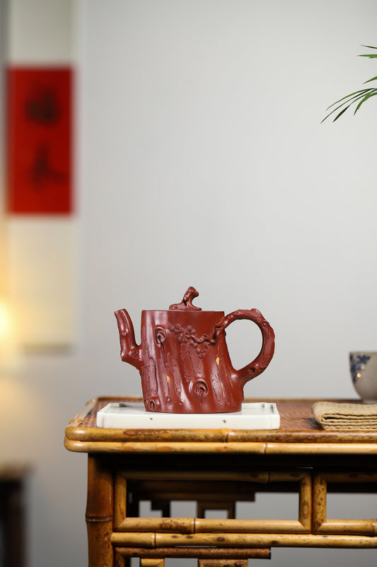Handmade Yixing purple sand teapot resembling a tree trunk, showcased on a wooden table.