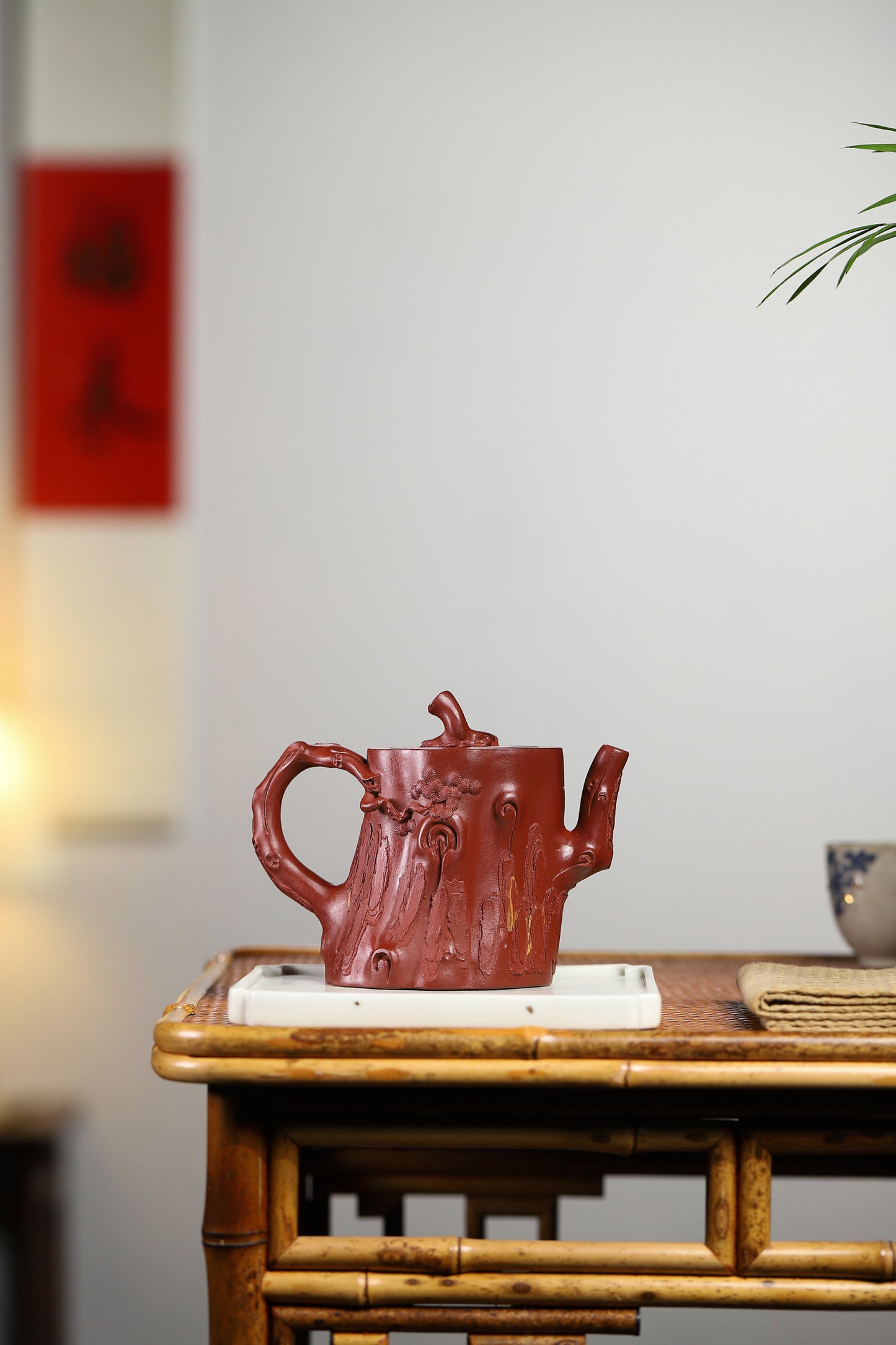 Handmade Yixing purple sand teapot styled like a pine tree branch, showcasing exquisite craftsmanship on a wooden table.