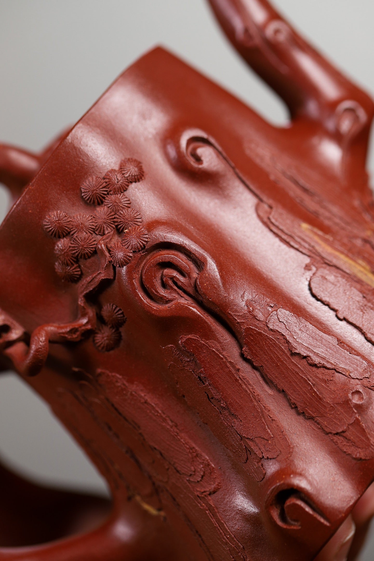 Handmade Yixing purple sand teapot featuring intricate pine tree details and textured bark design, showcasing exquisite craftsmanship.