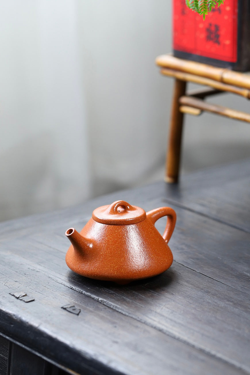 Handmade Yixing purple sand teapot with a glossy finish, elegantly placed on a dark wooden surface.