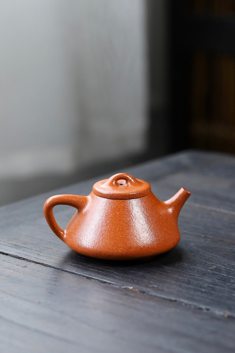 Handmade Yixing purple sand teapot with a smooth finish on a wooden table.
