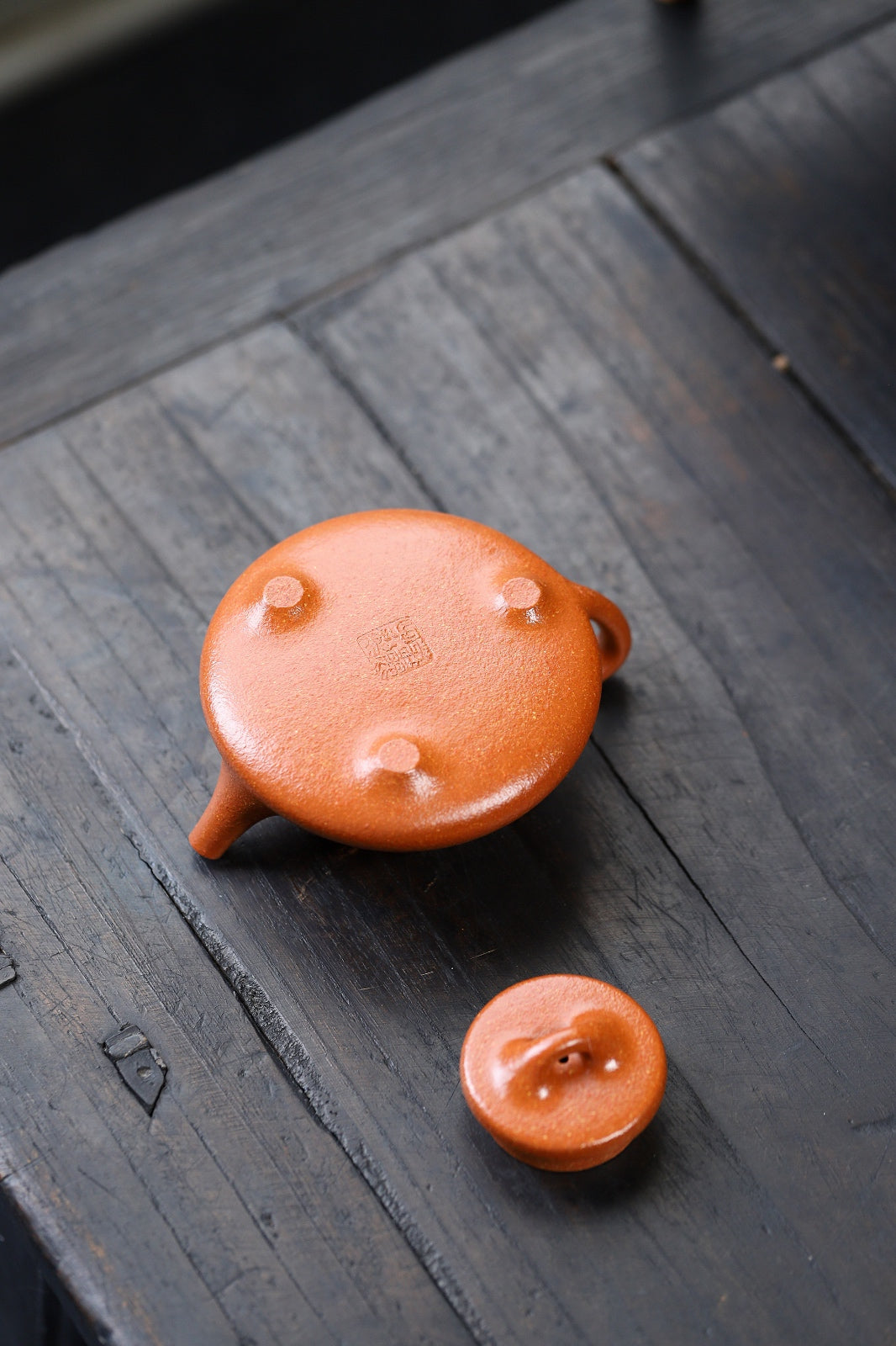 Handmade Yixing purple sand teapot with matching lid, showcasing unique craftsmanship and vibrant orange color.