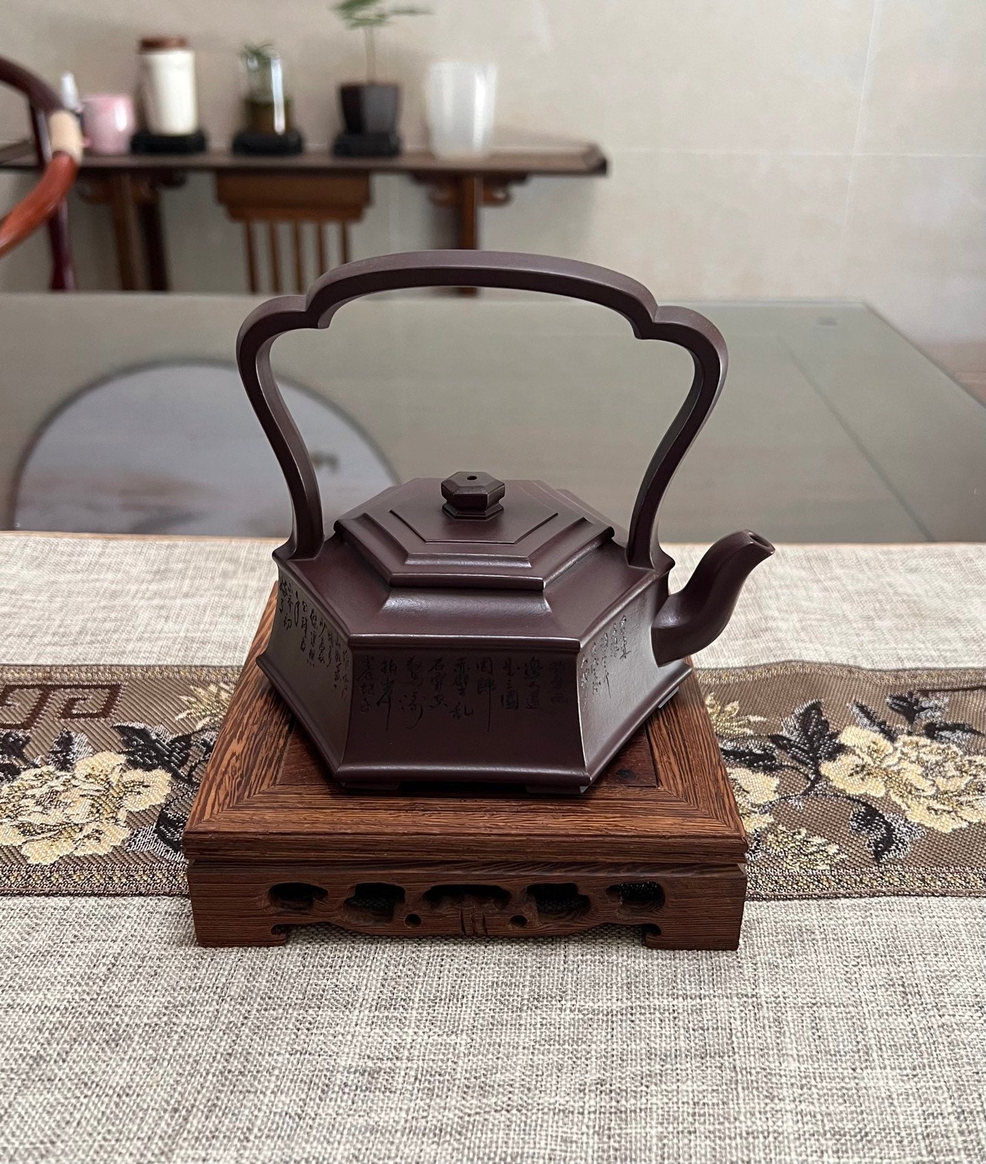 Handmade Yixing purple sand teapot with six-sided design on a wooden base, showcasing elegant craftsmanship.
