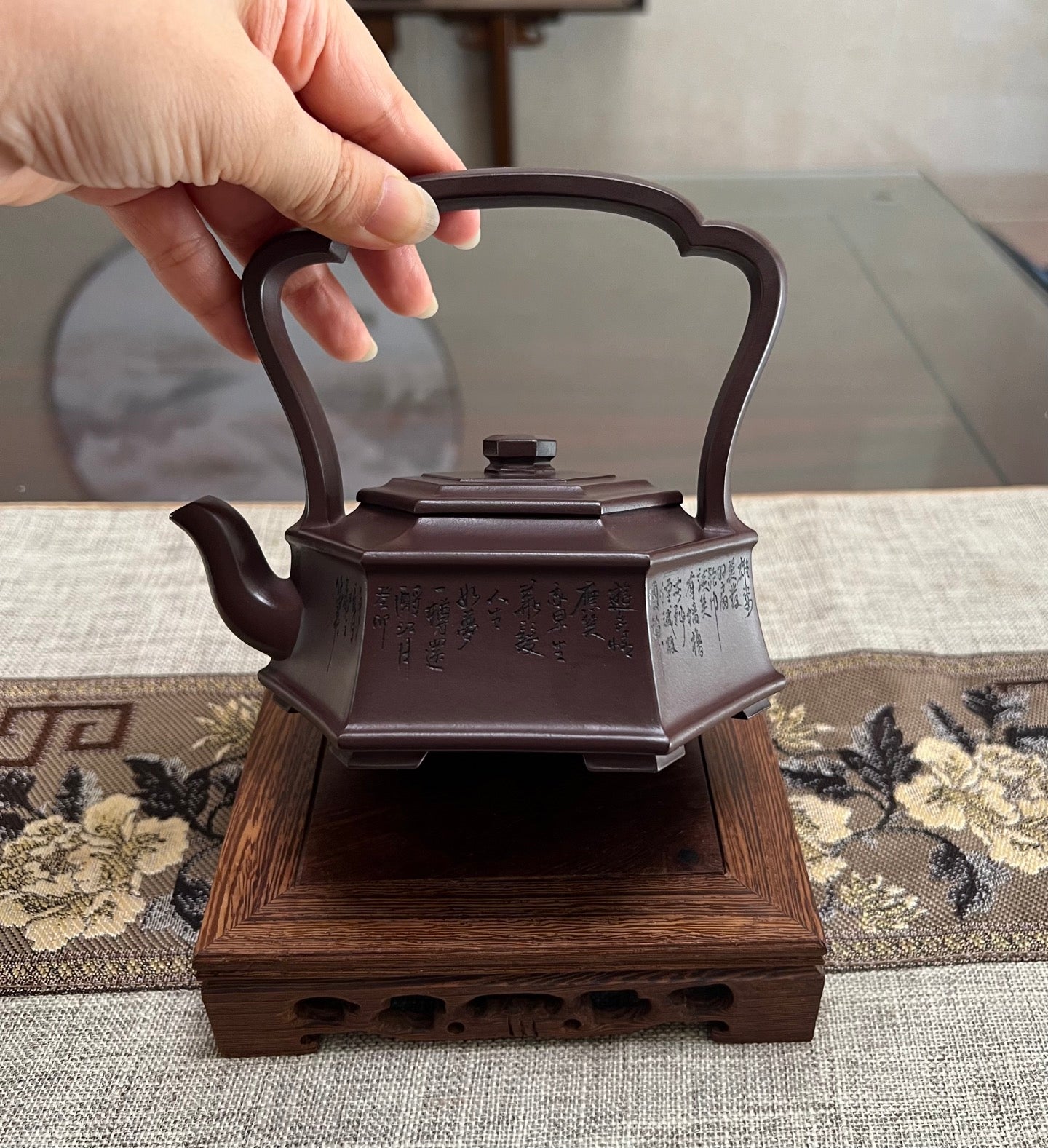 Handmade Yixing purple sand teapot with a six-sided design, held by a hand, showcasing its unique shape and craftsmanship.