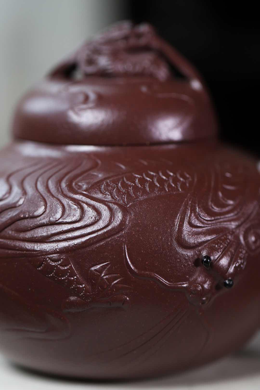 Handmade Yixing purple sand teapot featuring intricate dragon and fish scale designs, showcasing traditional craftsmanship.