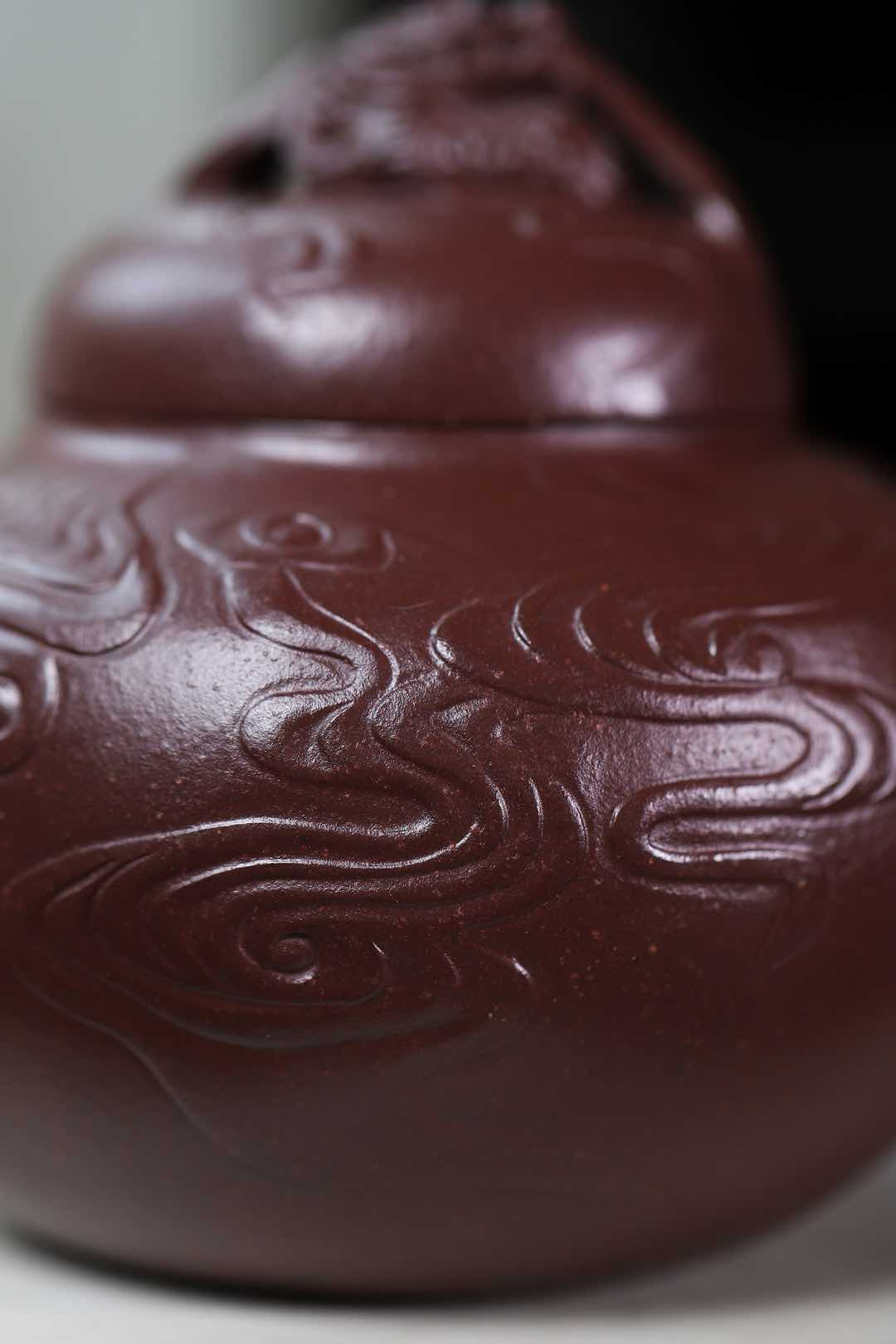 Handmade Yixing purple sand teapot featuring intricate swirling patterns and a detailed lid design.