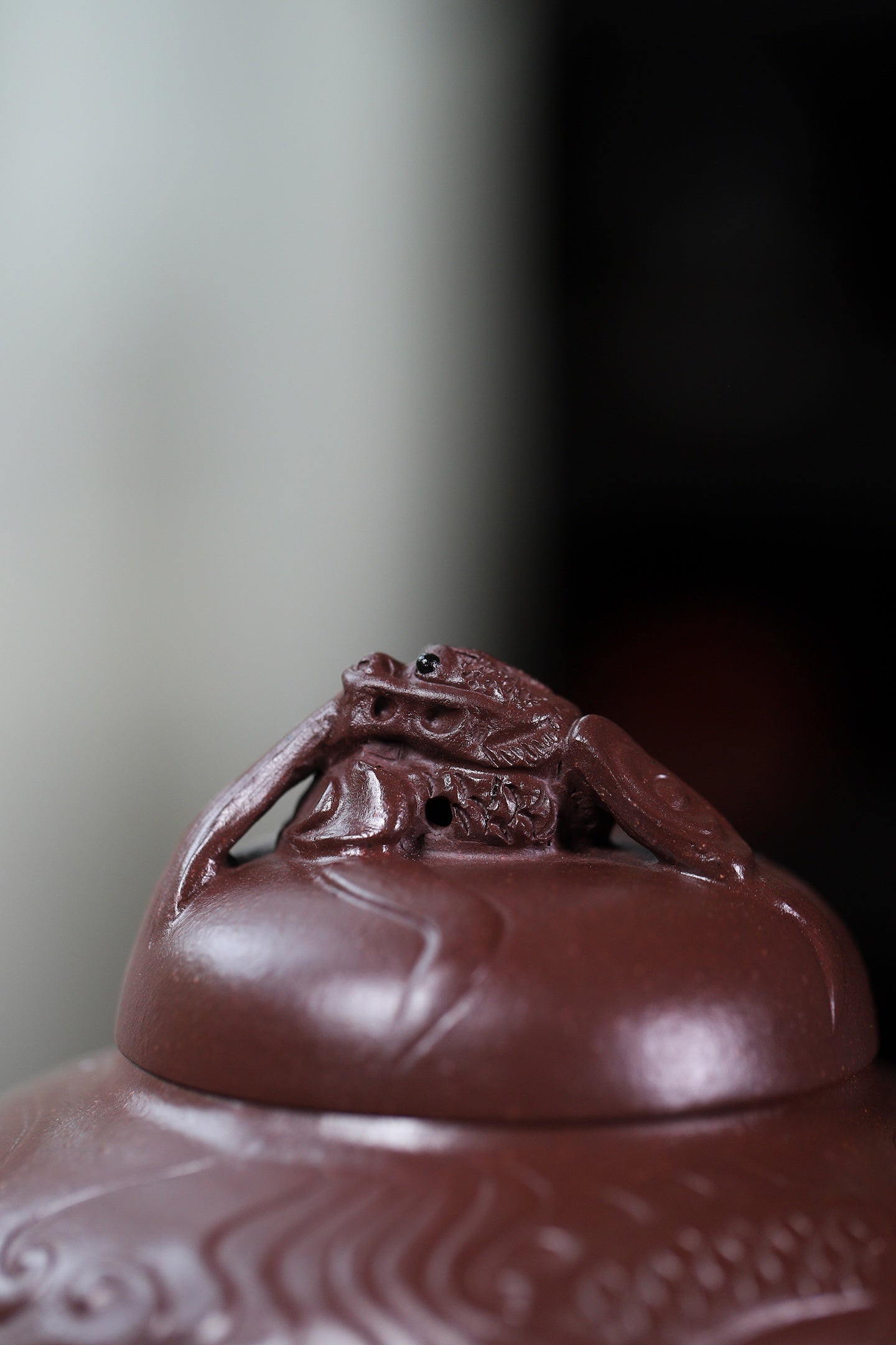 Close-up of handcrafted Yixing purple sand teapot lid featuring a detailed frog design.