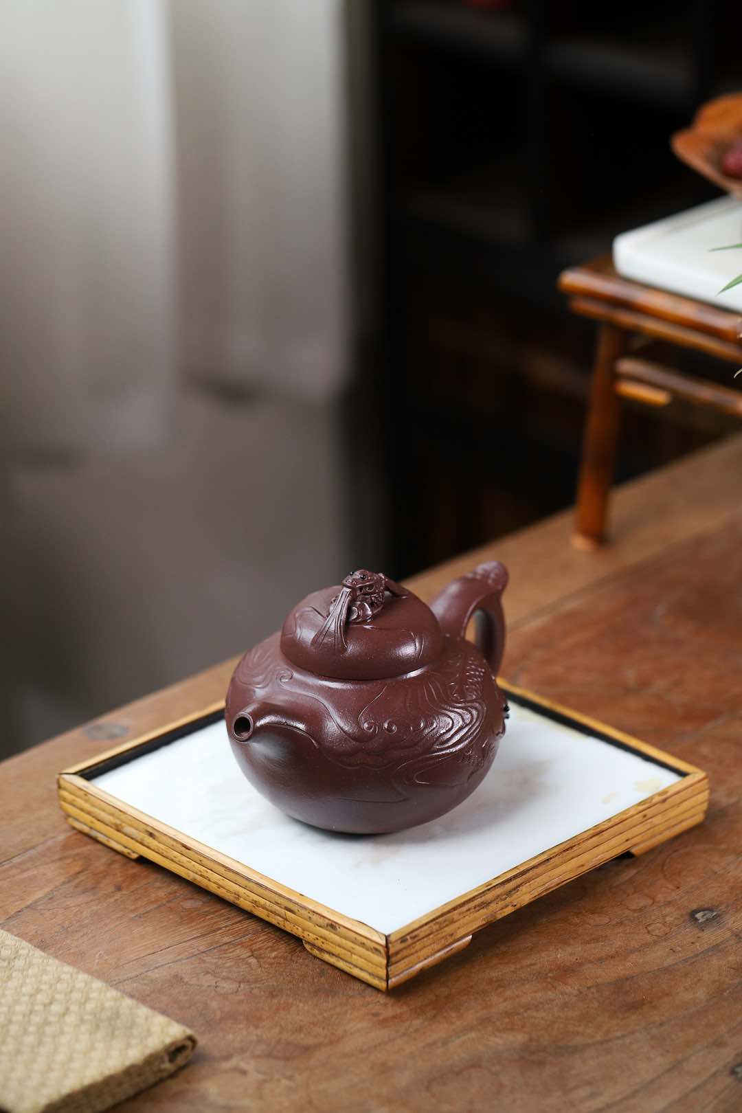 Handmade Yixing purple sand teapot featuring traditional dragon design on a wooden tray.