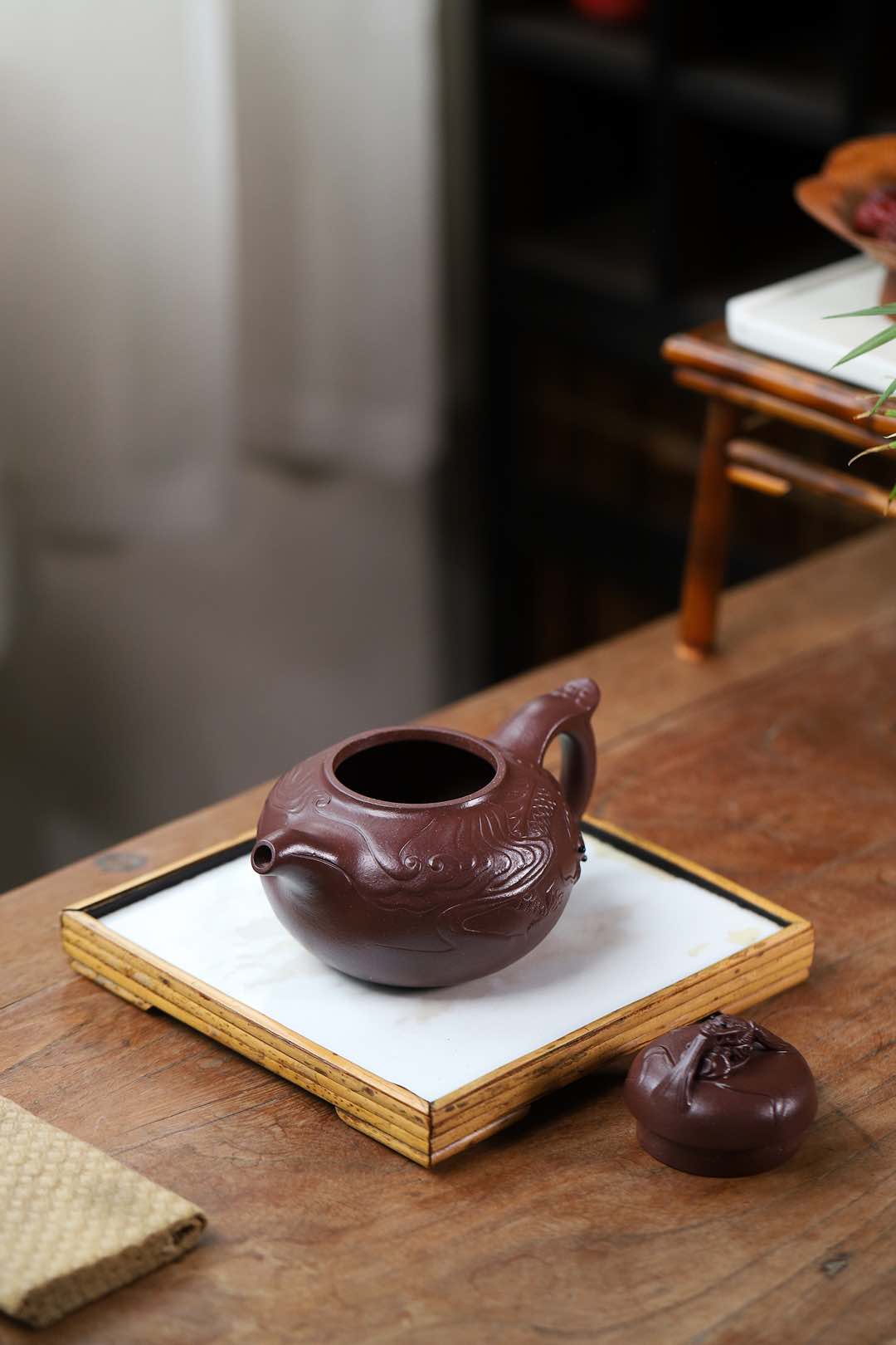 Handmade Yixing purple sand teapot on a wooden tray, showcasing intricate design and craftsmanship.