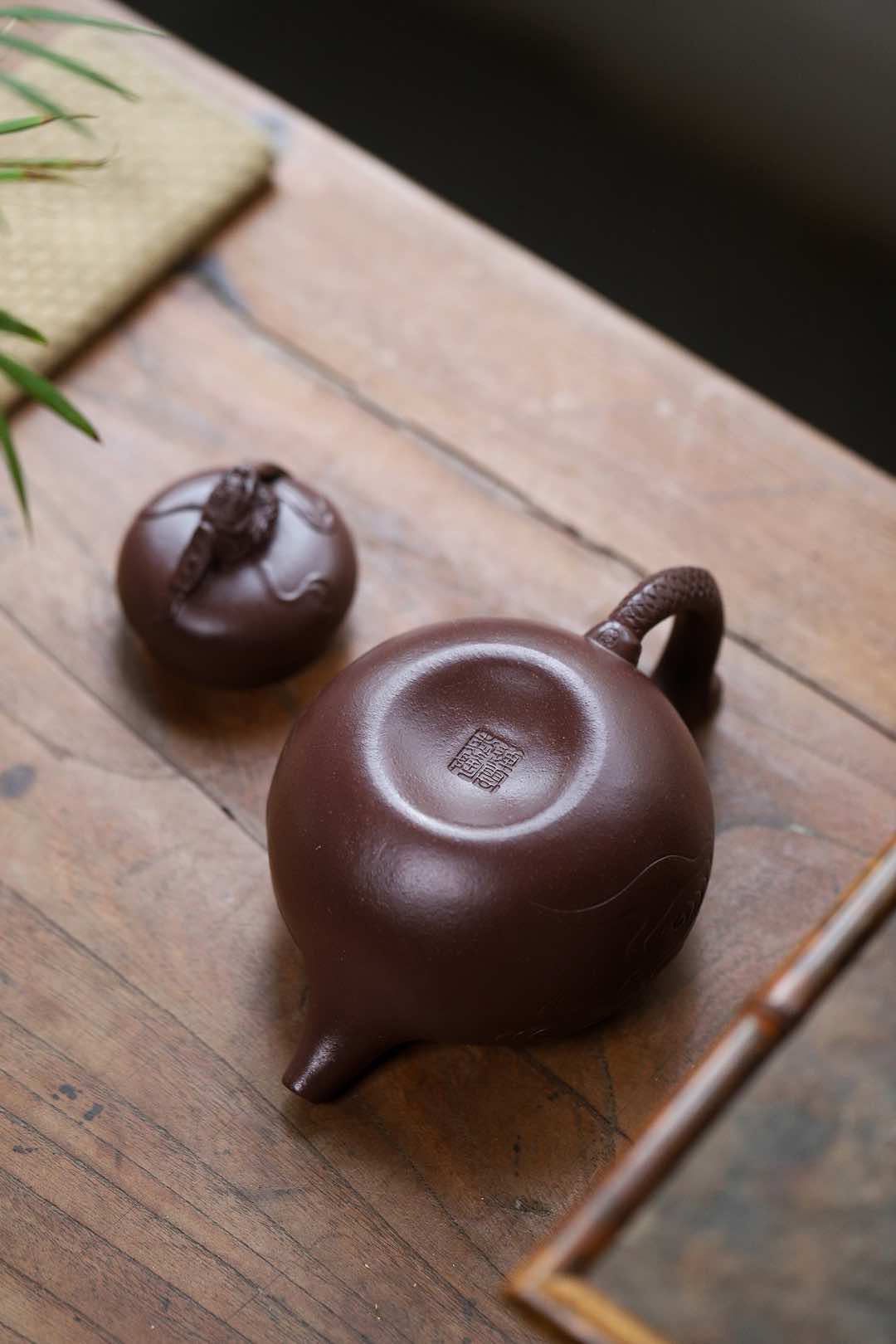 Handmade Yixing purple sand teapot and lid on wooden table, showcasing traditional design and craftsmanship.