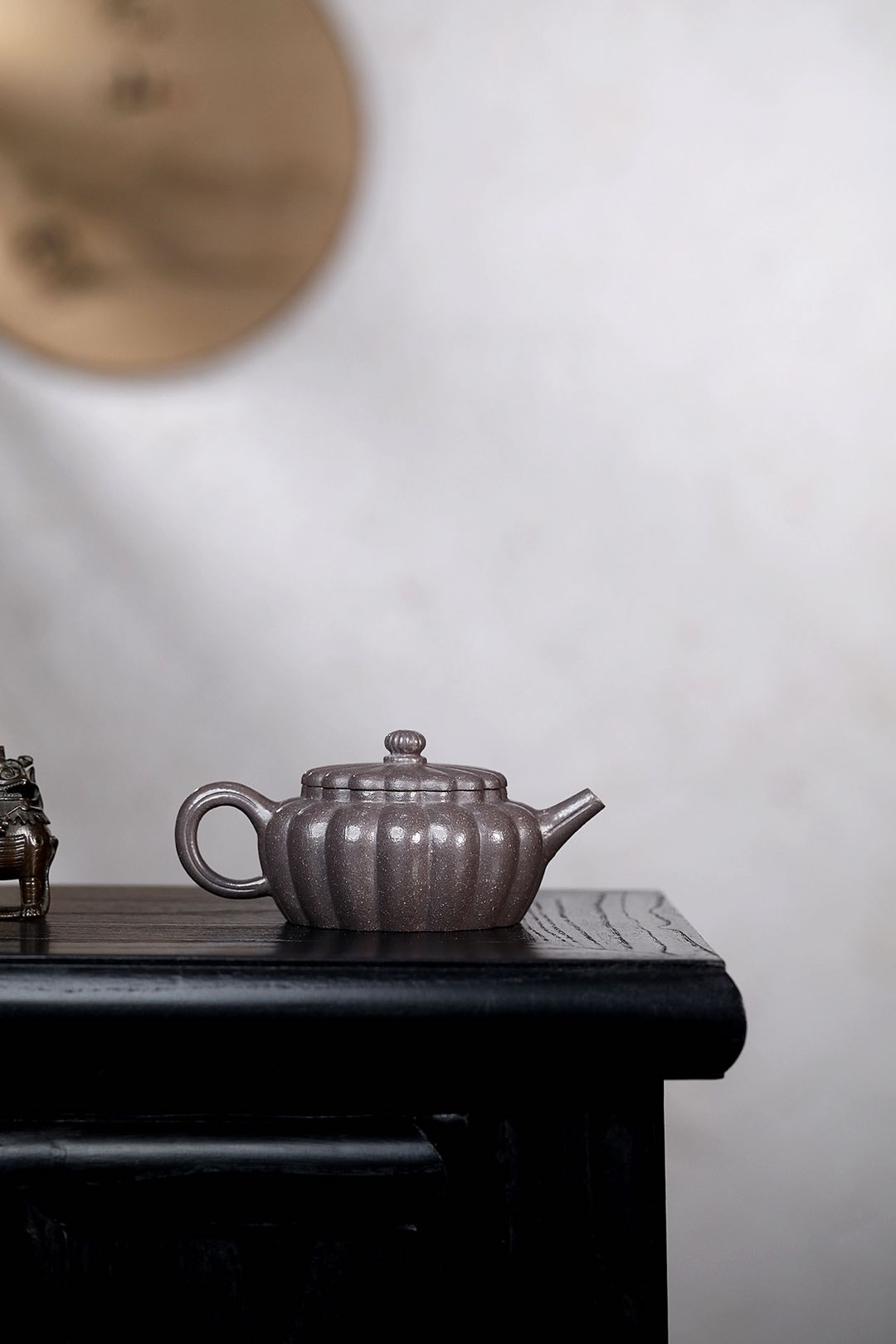 Handmade Yixing purple sand teapot on a black wooden surface, showcasing its elegant design.
